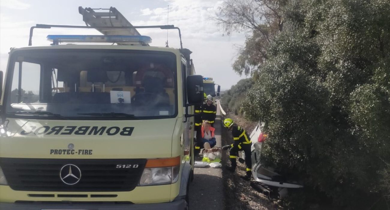 Bomberos y personal sanitario, atendiendo a la persona accidentada tras volcar su coche, en el lugar del siniestro.