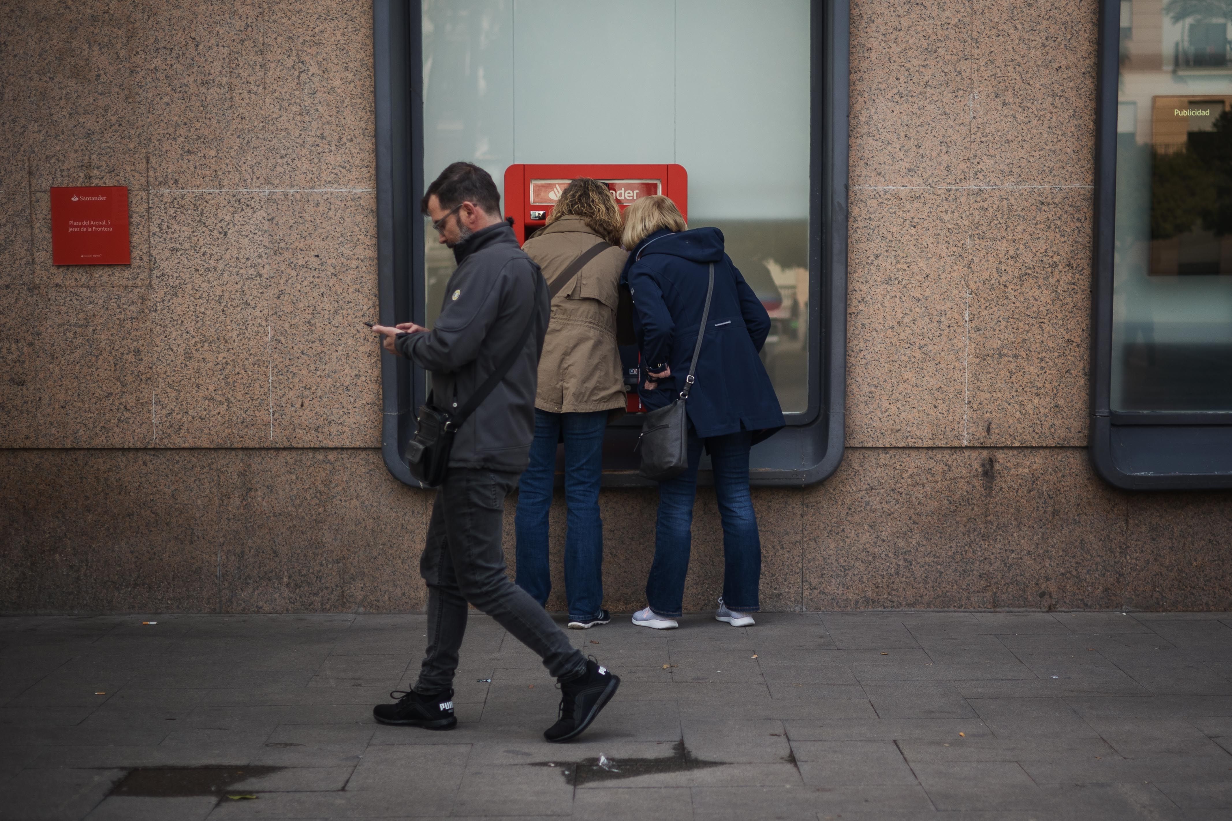 Dos personas sacan dinero con la tarjeta bancaria en una imagen de archivo. 