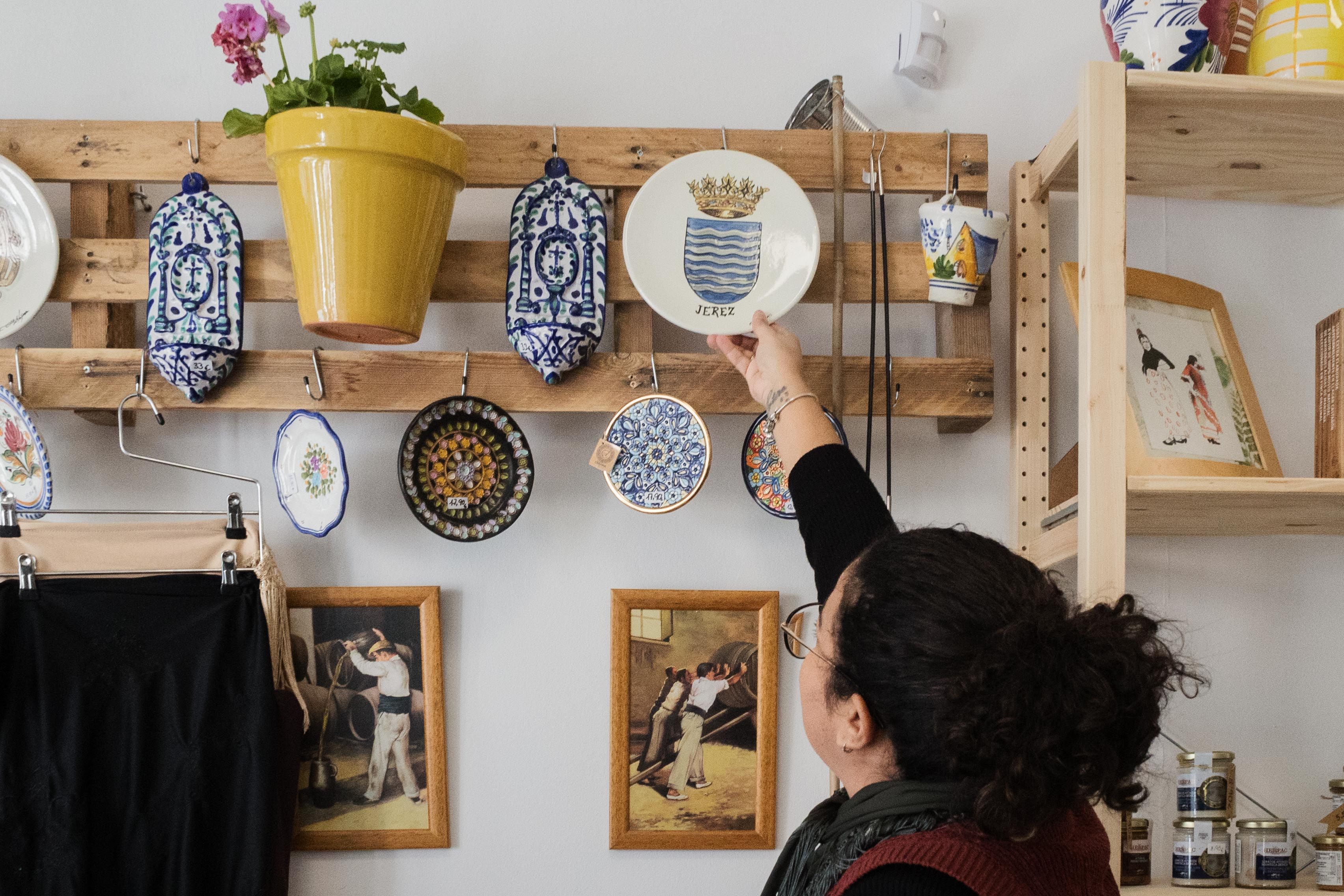 Colocando un plato de cerámica con el escudo de Jerez en el expositor.    CANDELA NÚÑEZ