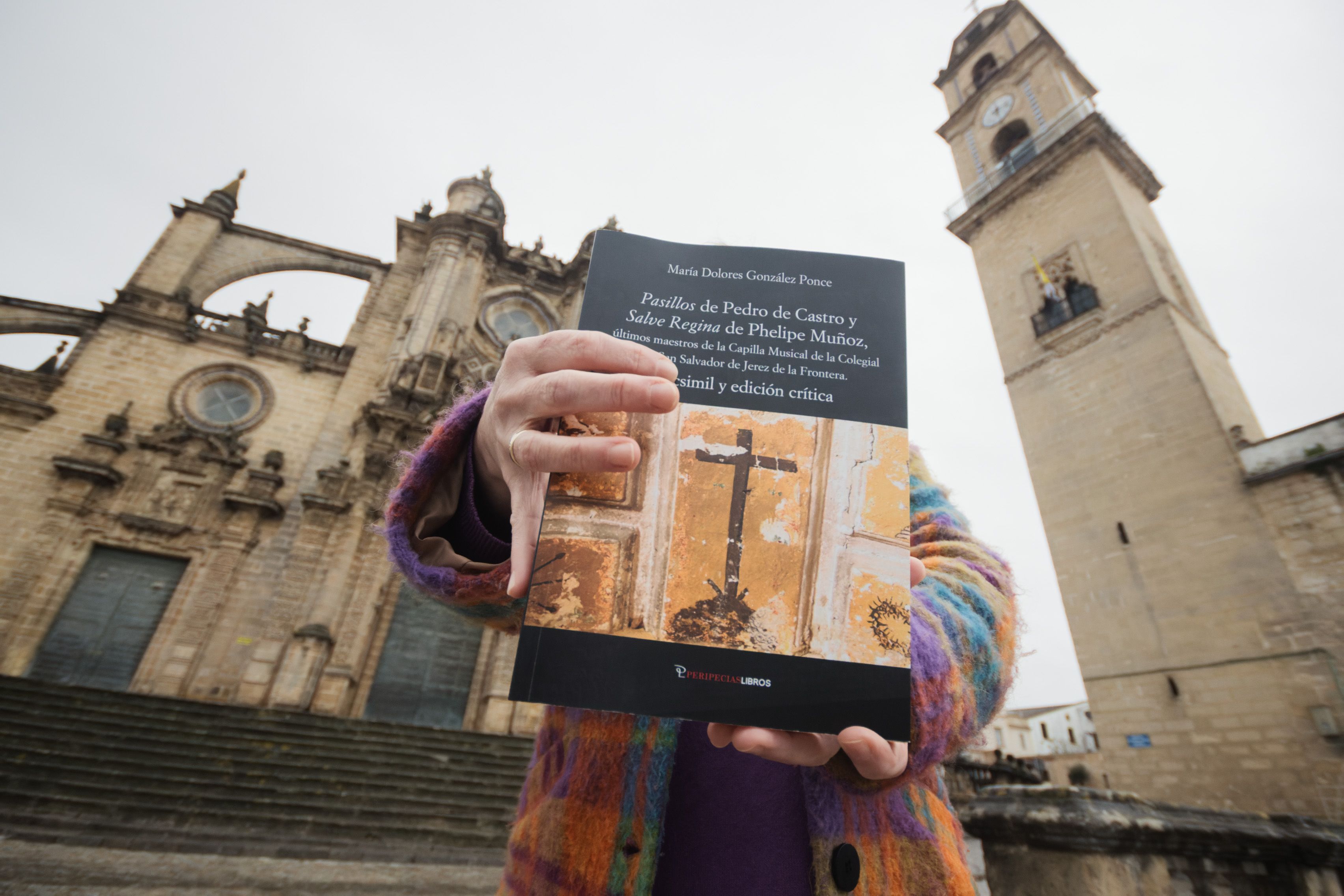 Lola González Ponce muestra, con la Catedral al fondo, la portada de su libro.