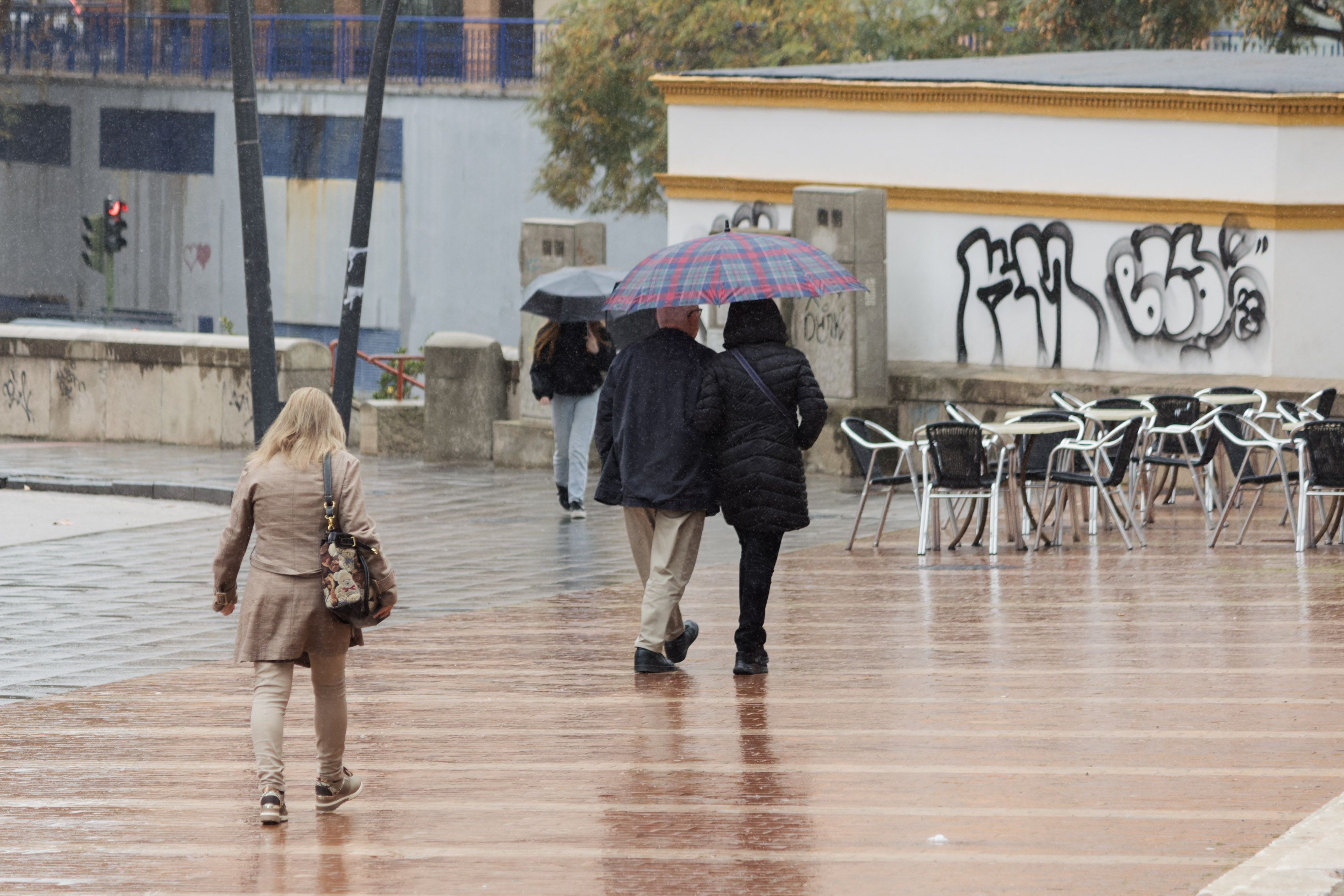 Varias personas pasean bajo la lluvia en Andalucía. Varias personas pasean bajo la lluvia en Andalucía.