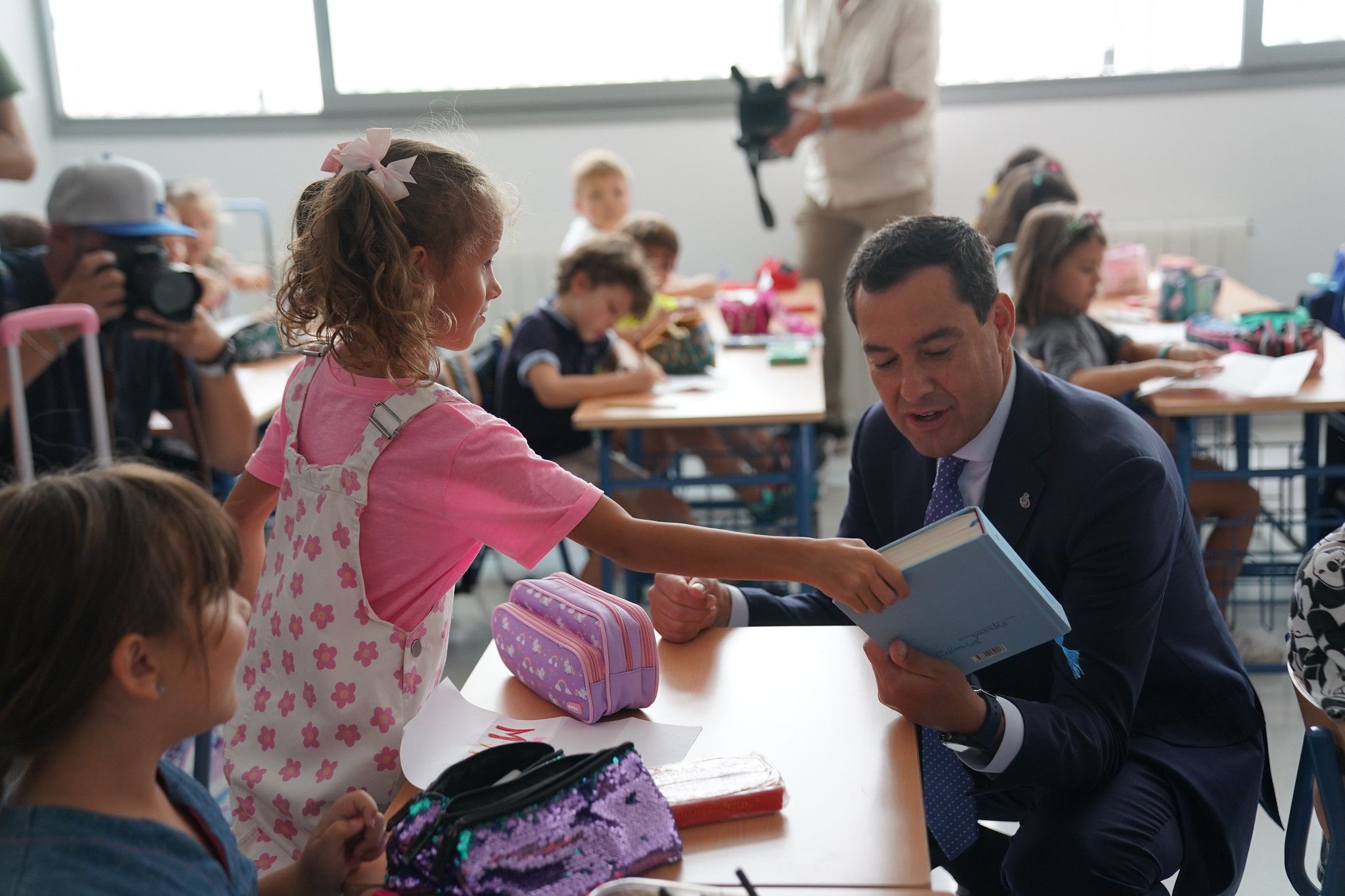 El presidente de la Junta de Andalucía, Juanma Moreno, con una alumna que le muestra un libro.