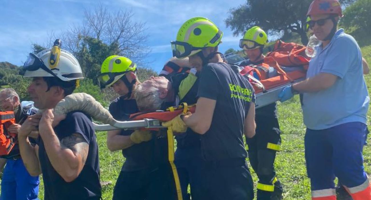 Bomberos trasladando en camilla al hombre accidentado.