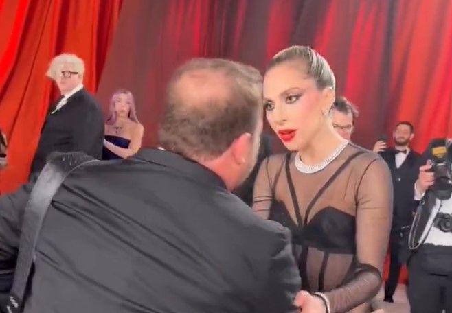 Lady Gaga ayuda a un cámara en los Oscars. 