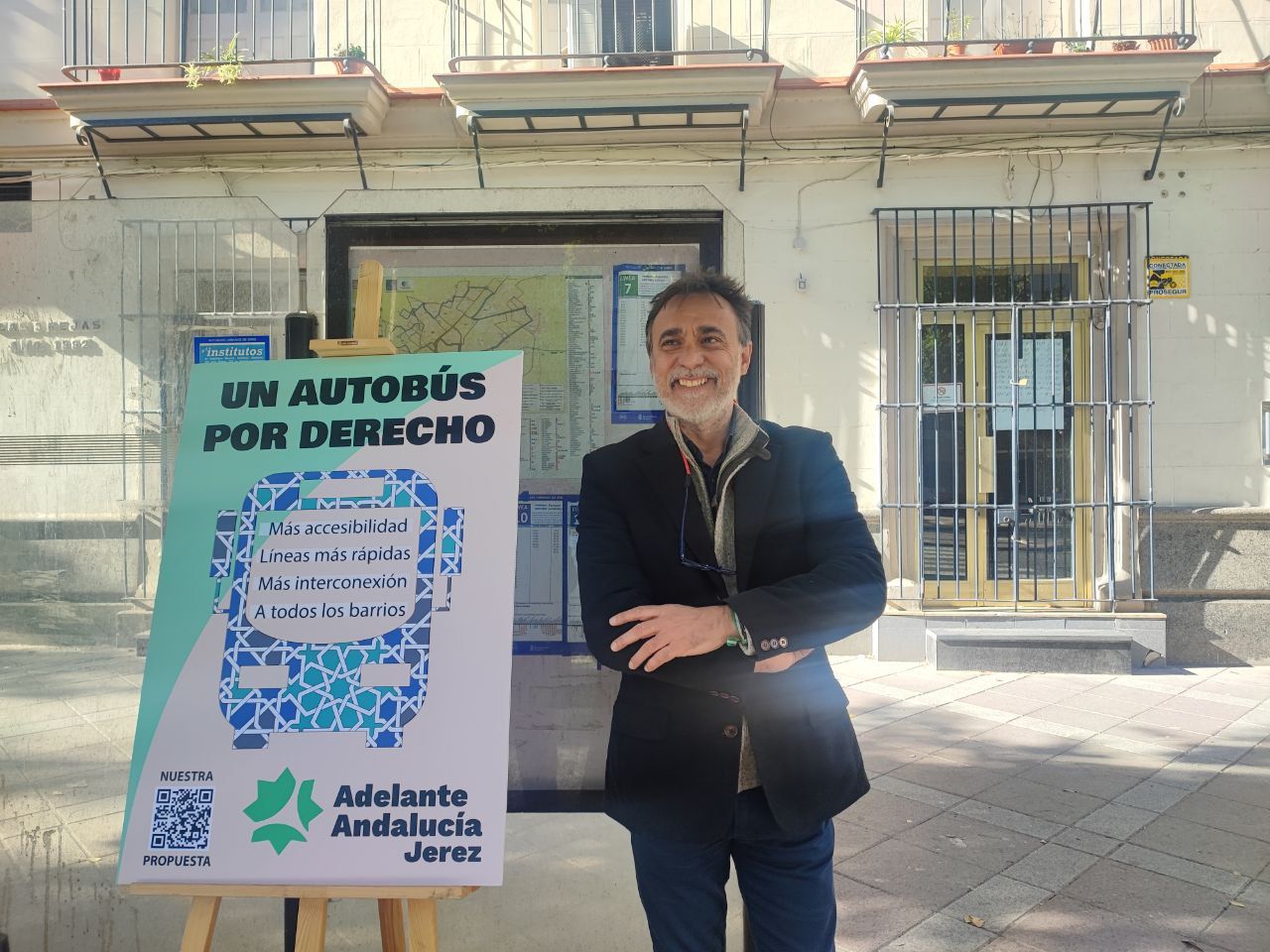 Adelante Andalucía propone autobuses cada 5 minutos en todos los barrios de Jerez. En la imagen, el candidato, Carlos Fernández, junto a un cartel que expone la campaña. 