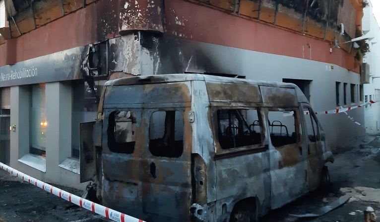 La furgoneta incendiada, junto al edificio que afectó en Algeciras.