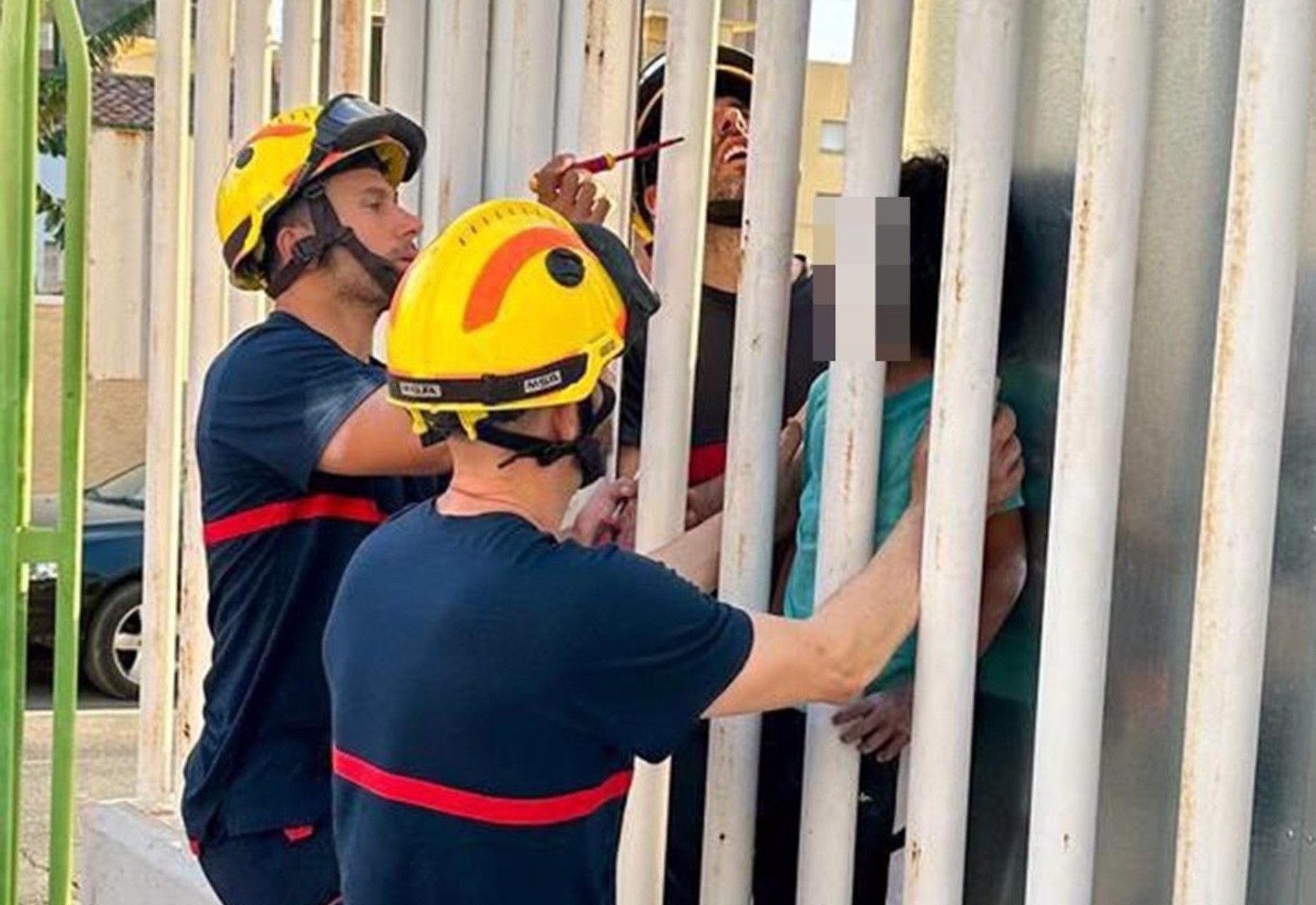 Bomberos ayudan a un niño atrapado en el interior de una valla. 