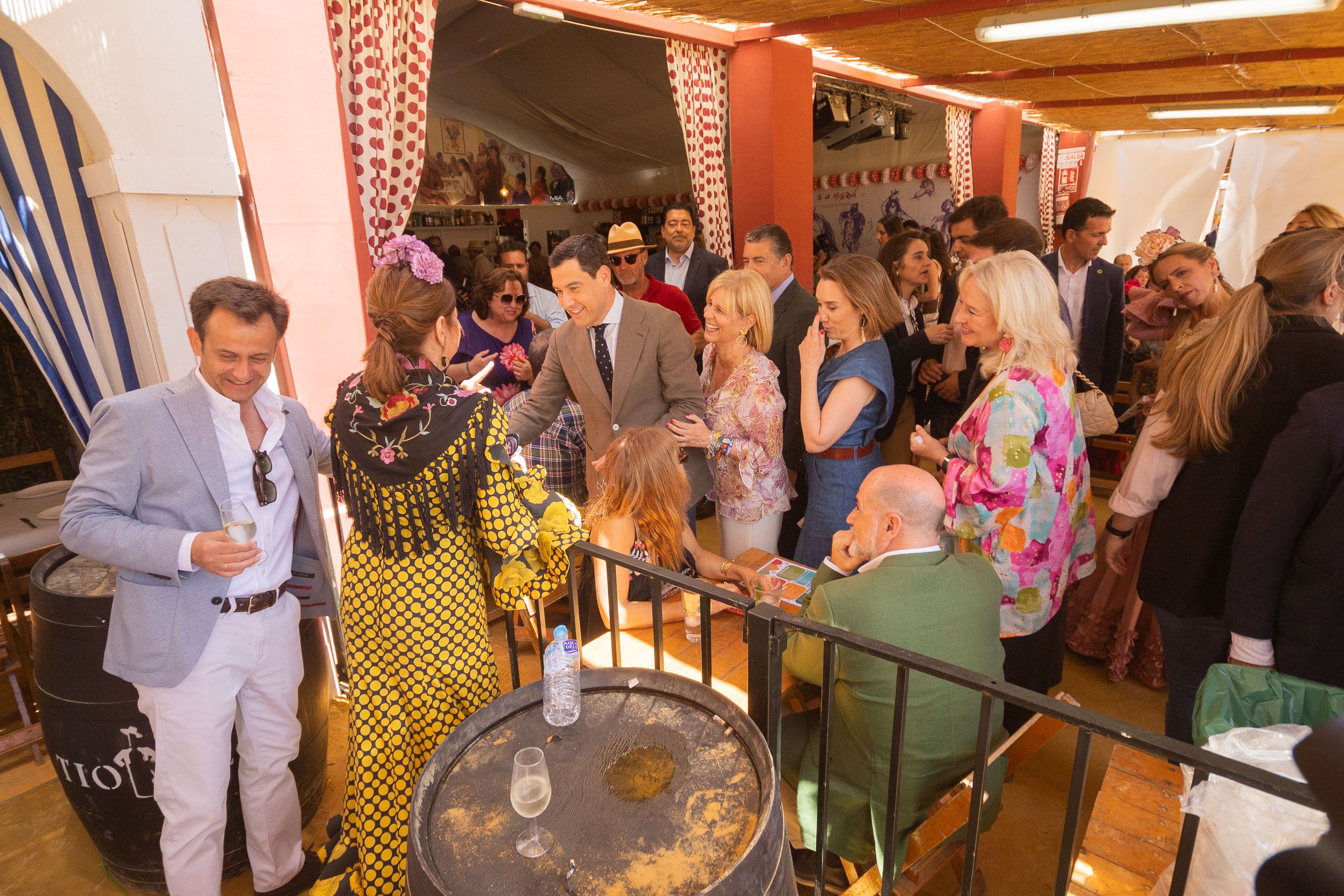 Juanma Moreno, presidente de la Junta y del PP andaluz, hablando con una mujer vestida de gitana en la Feria del Caballo en el inicio de la campaña.