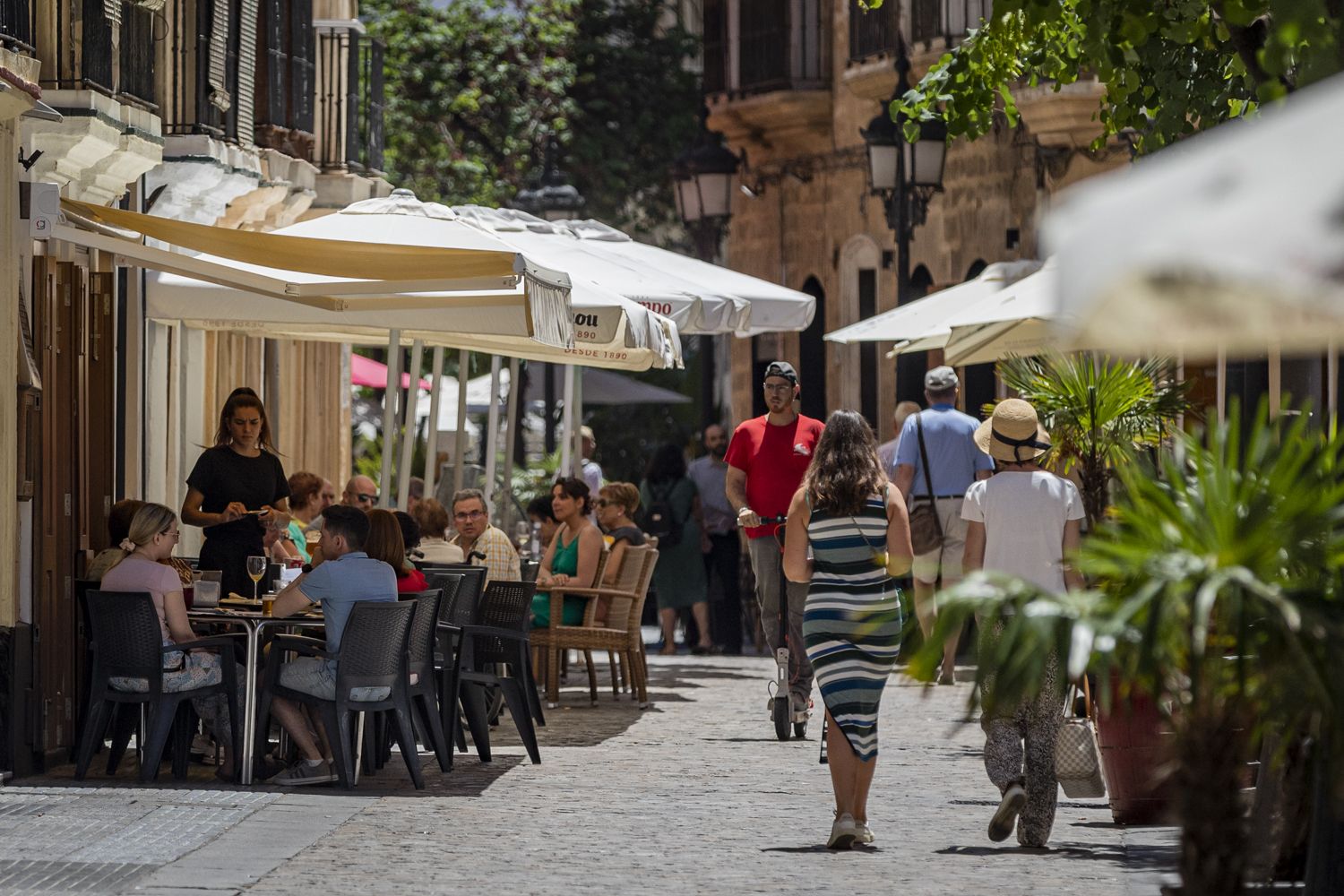 Peatones junto a las terrazas de la calle Plocia de Cádiz, este verano.