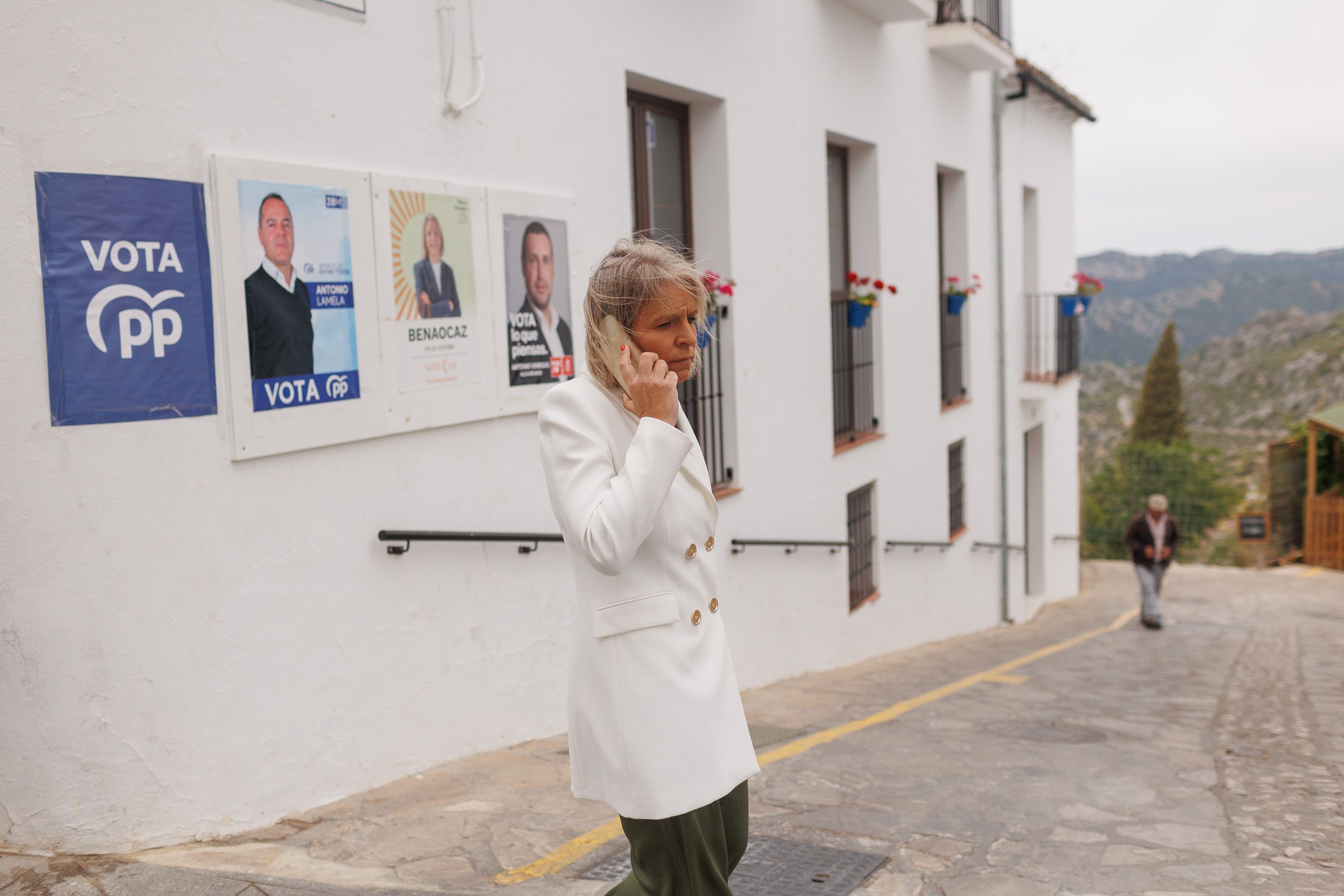 Olivia Venegas, alcaldesa, de Ciudadanos, la última alcaldesa 'naranja', pasa ante carteles electorales a unos metros del Ayuntamiento de Benaocaz.