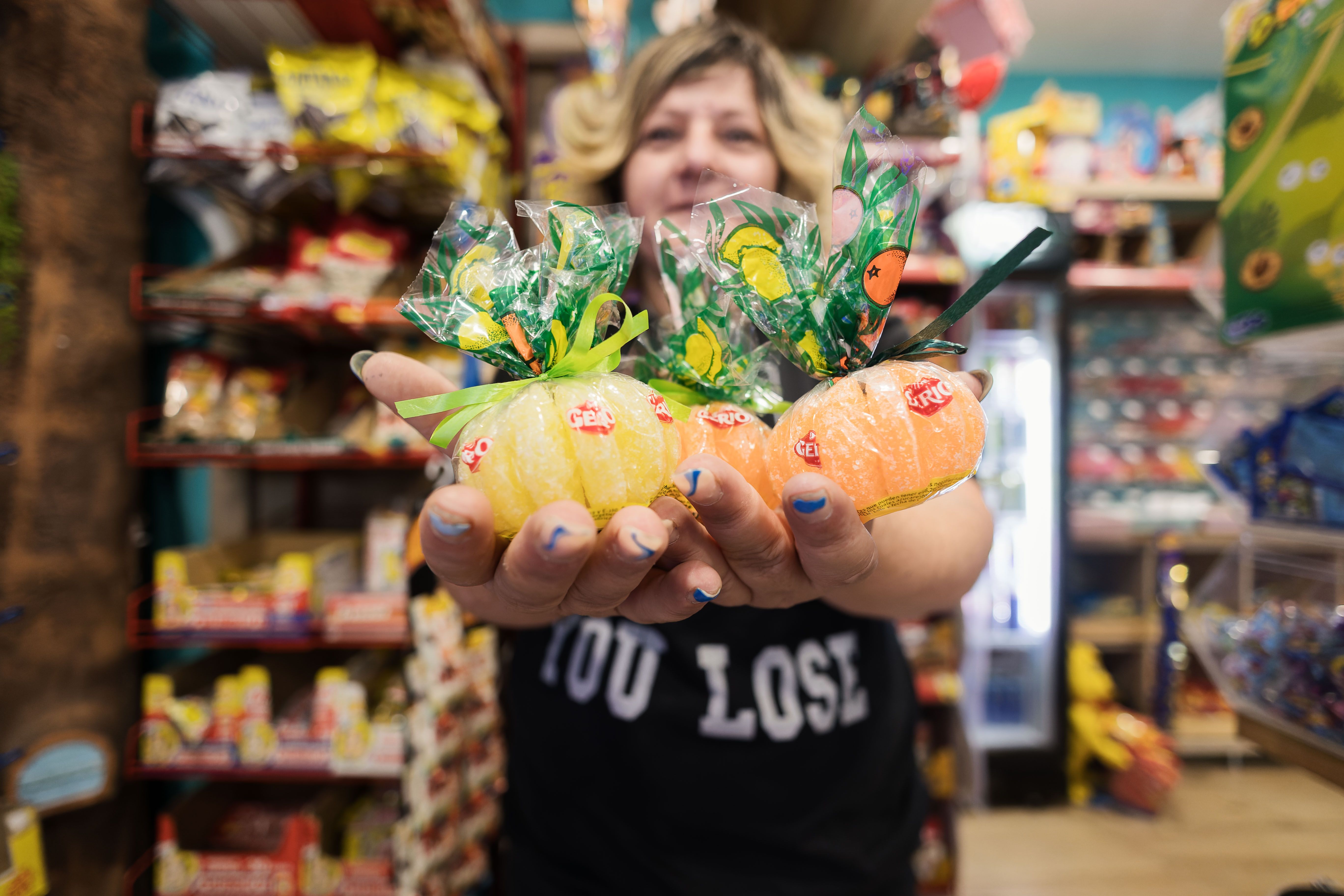 Eva en la tienda sosteniendo los clásicos gajos de naranja y limón, una de las golosinas más veteranas.