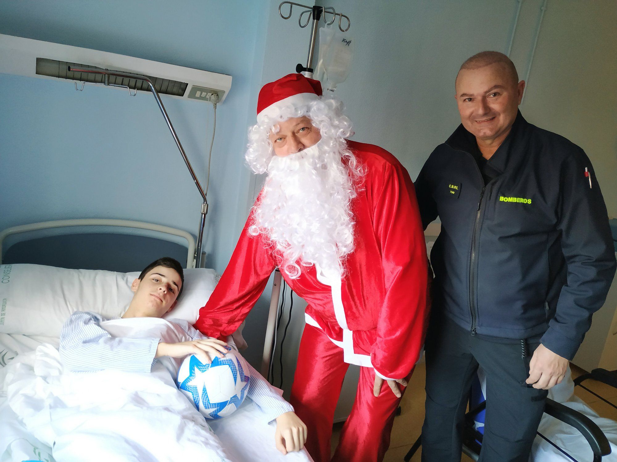 Un menor hospitalizado recibe un regalo de manos de Papá Noel y un bombero de Jerez.
