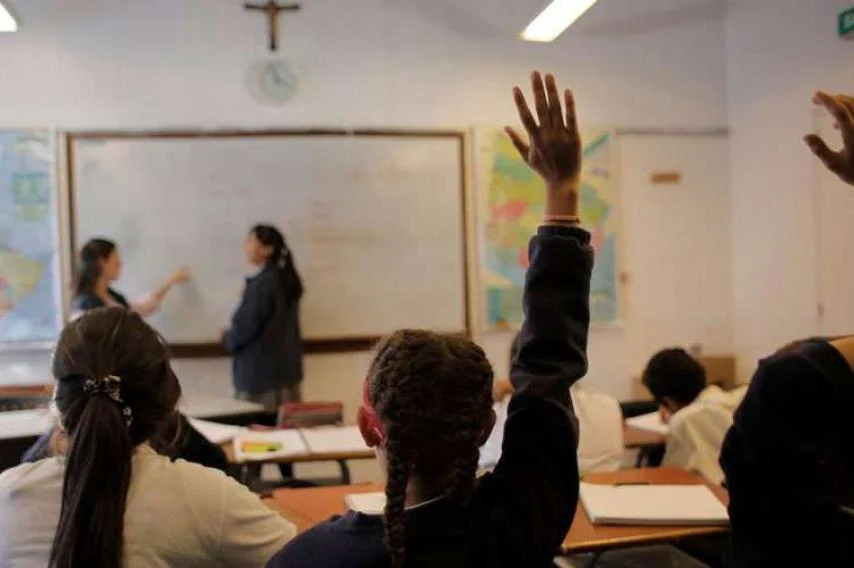 Una niña levanta la mano en una clase de religión, que quieren sacar del currículo escolar en Andalucía.