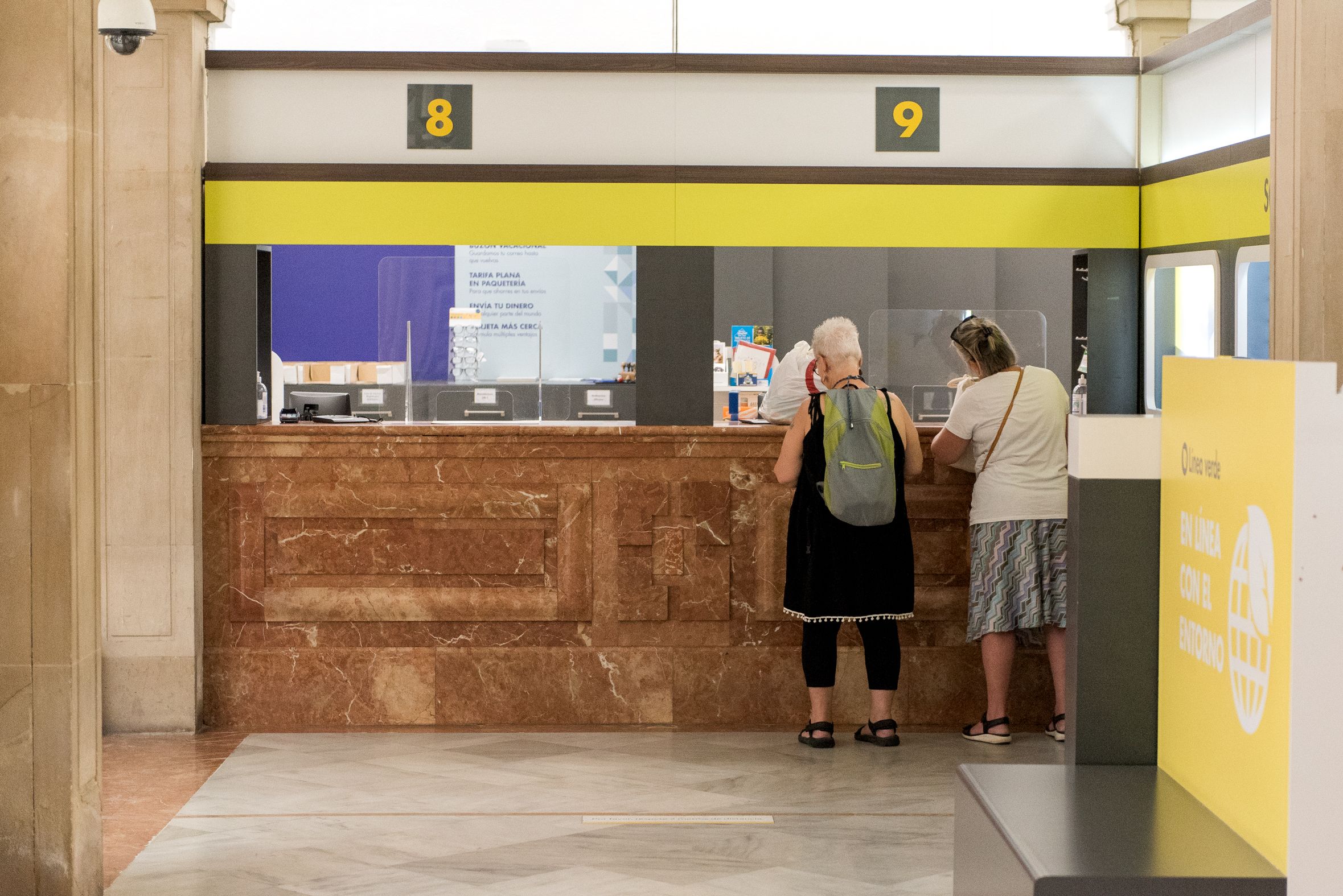 Dos personas solicitan su voto en una oficinas de Correos.