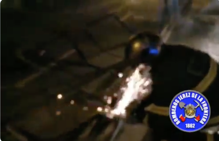 Un bombero, cortando la valla de la calle Medina.