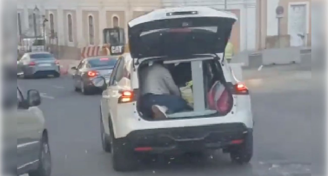Una persona, viajando en el interior de un coche con la puerta del maletero abierta.
