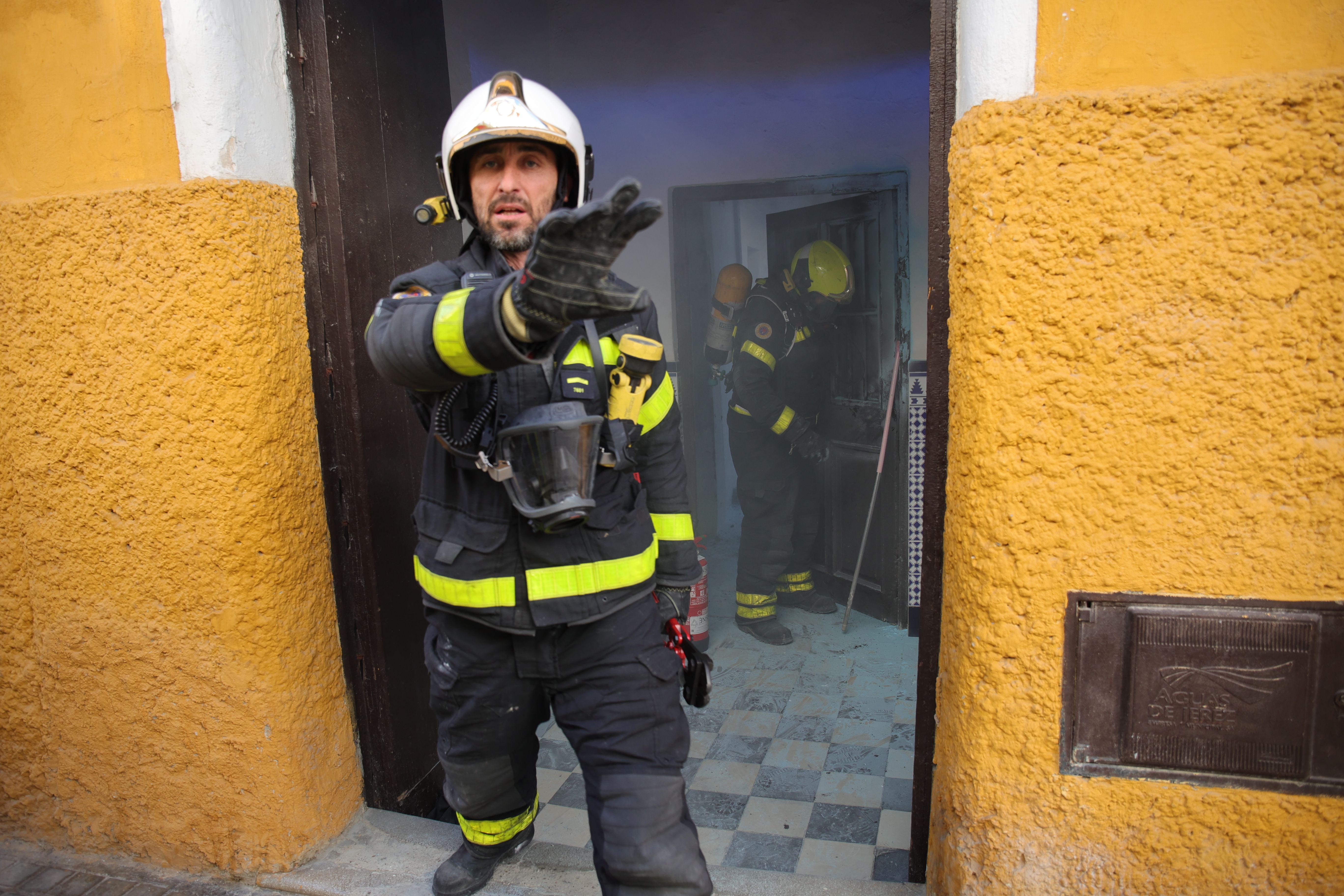 Bomberos en el portal del patio de vecinos de la calle Escuelas.