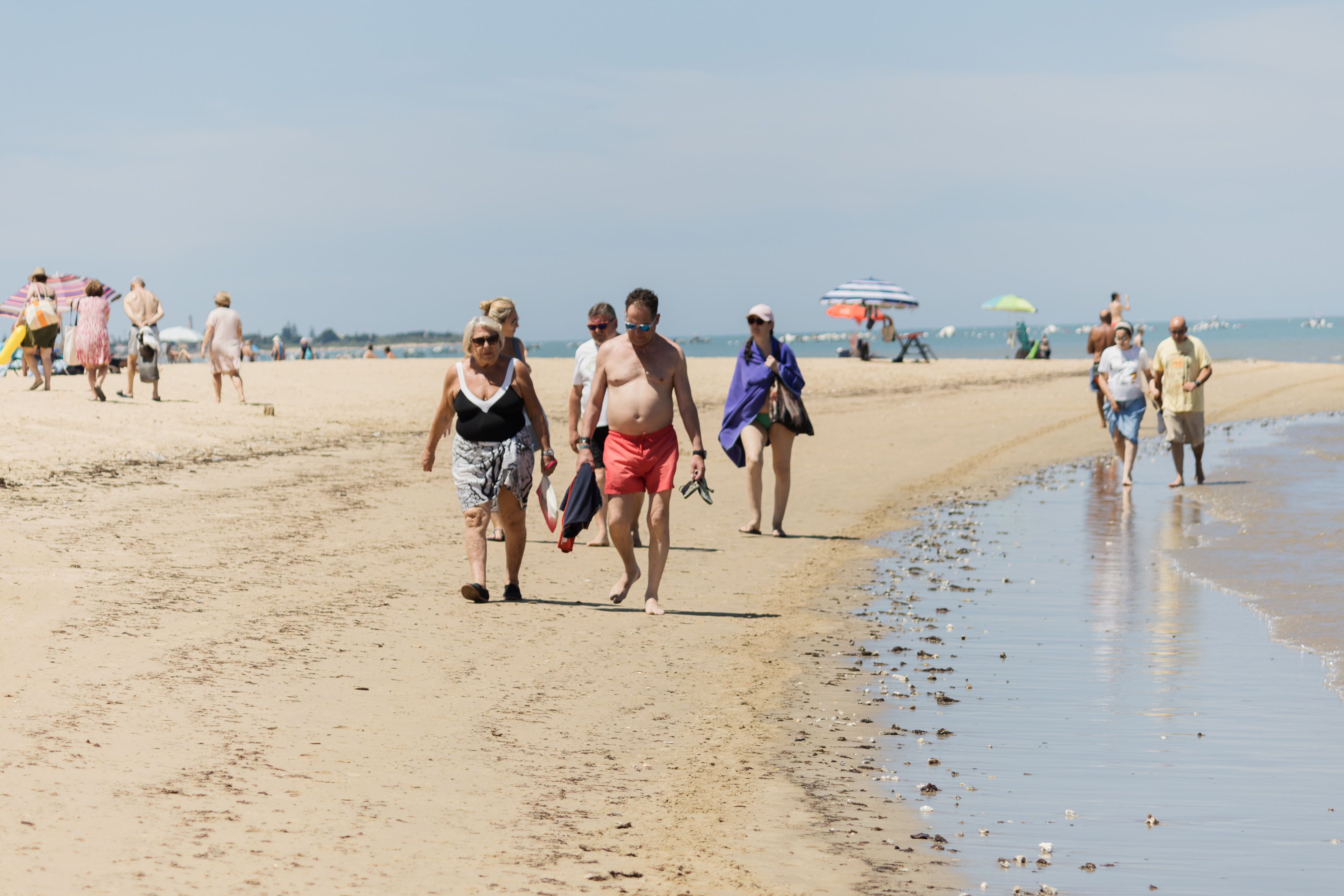Parejas de jubilados paseando por la playa de Sanlúcar, elegida mejor lugar para jubilarse, este verano