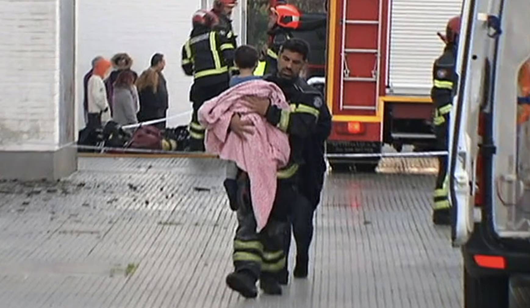 Un bombero rescata a uno de los menores del piso incendiado en La Hispanidad, en Huelva. IMAGEN: CANAL SUR