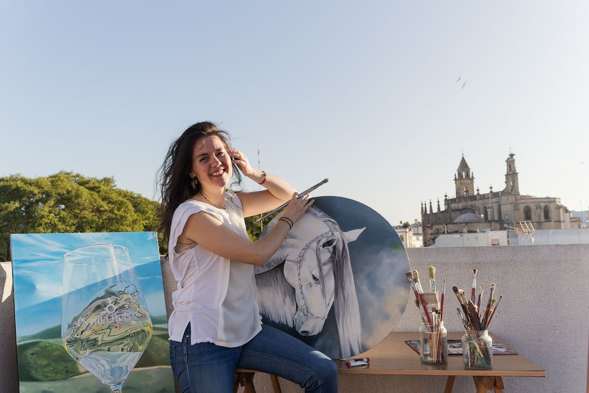 Leticia Millán Cobos en la azotea de su casa, junto a algunos de sus cuadros y la iglesia de Santiago al fondo. 