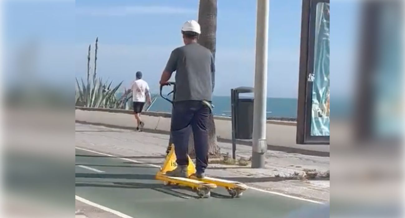Un obrero, con un portapalets por un carril bici de cádiz.