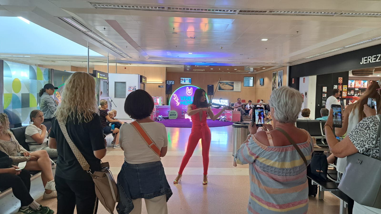 Música en directo en el Aeropuerto de Jerez para celebrar la llegada del verano. En la imagen, una violinista en la zona de embarque. 