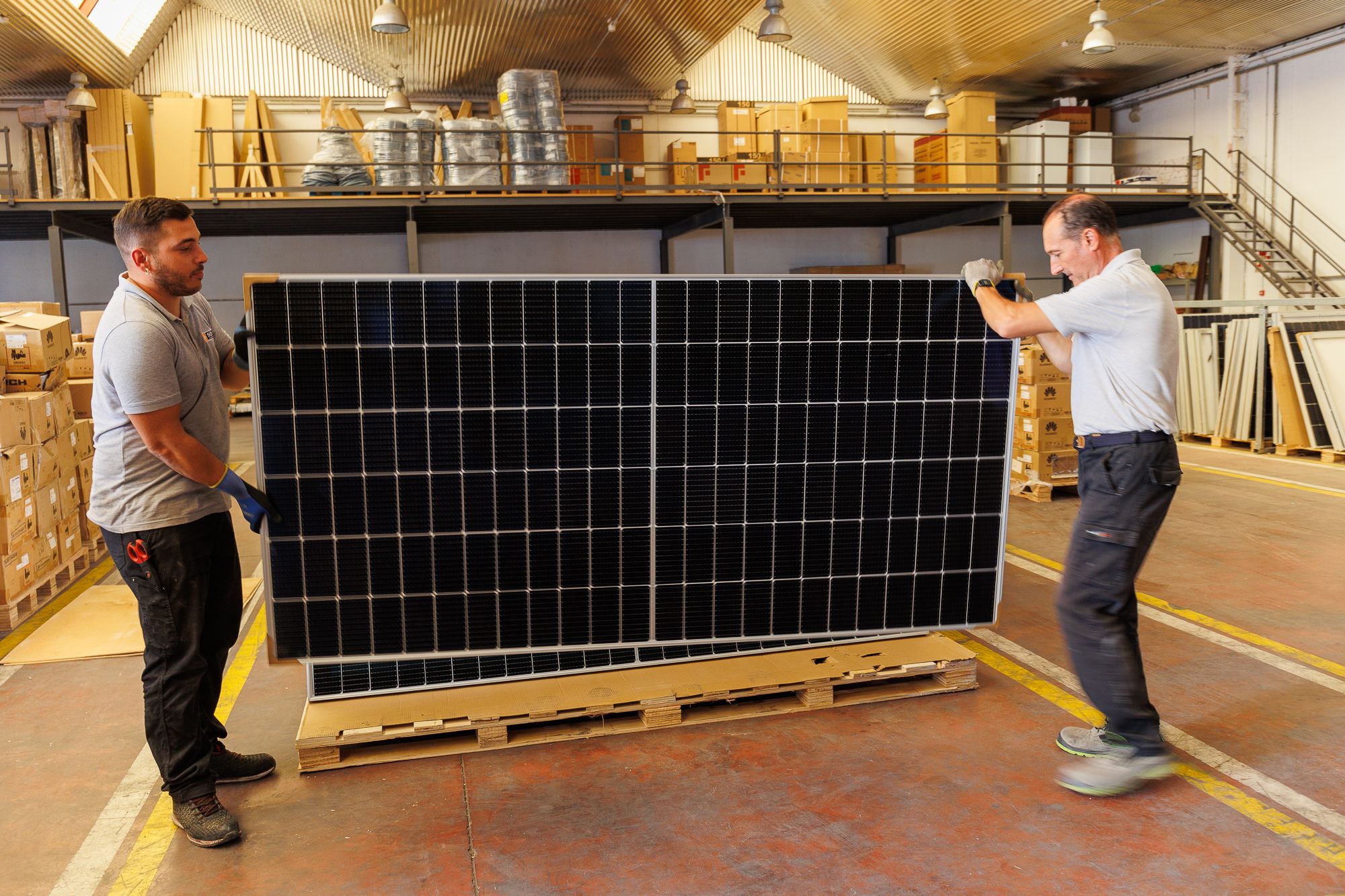 Dos trabajadores de Más Sol Energía, trasladando placas solares.