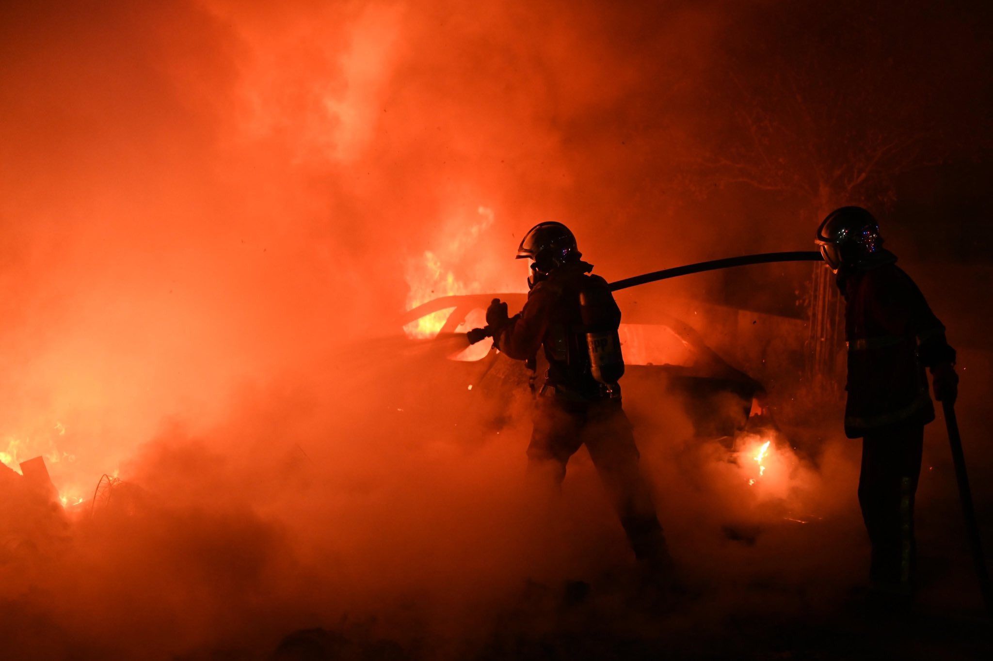 Bomberos de Francia, apagando fuegos provocados durante los disturbios en barrios.