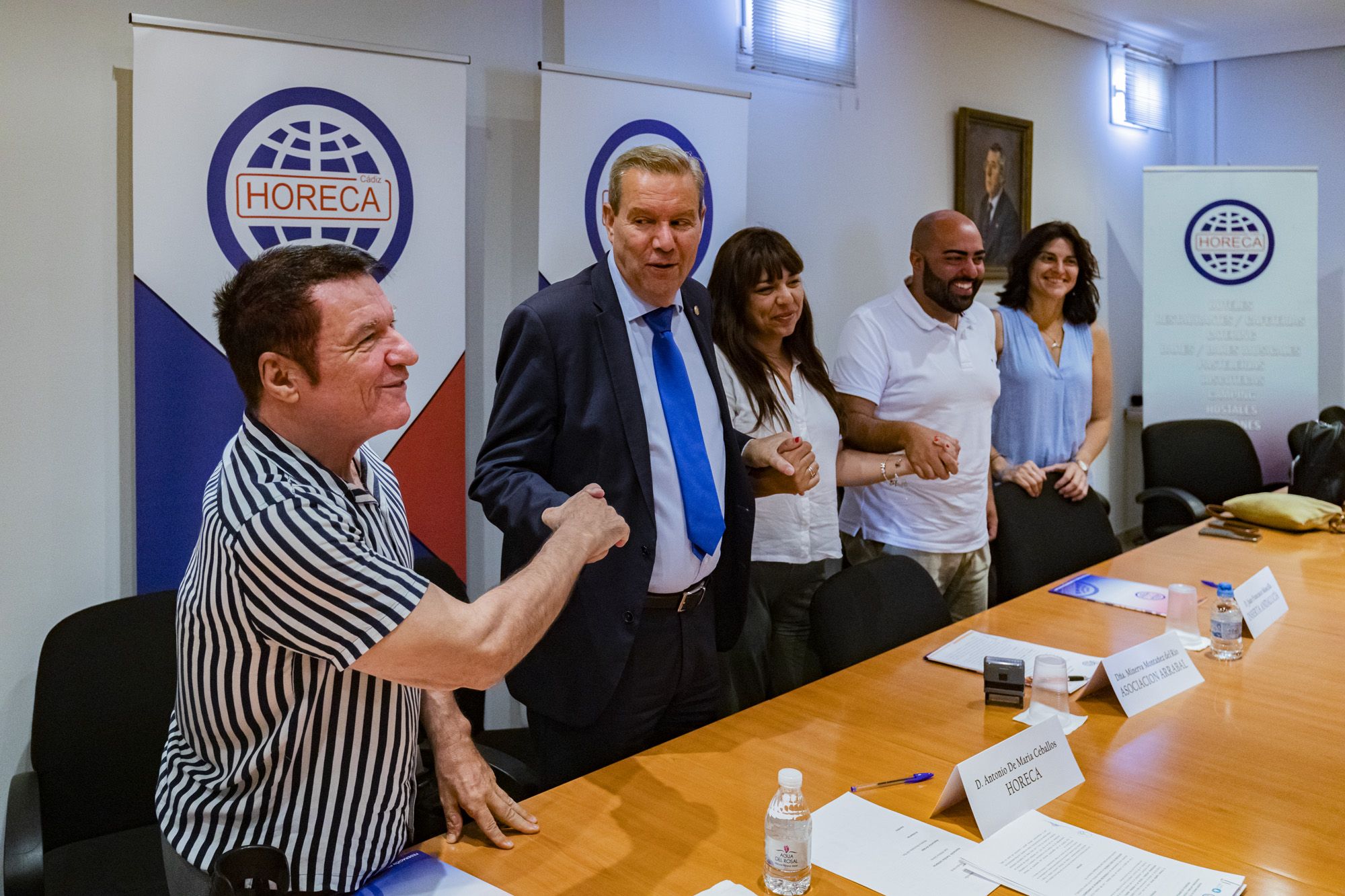 Los firmantes del convenio entre hostelería y los "jóvenes invisibles" entrelazan las manos al término del acto.