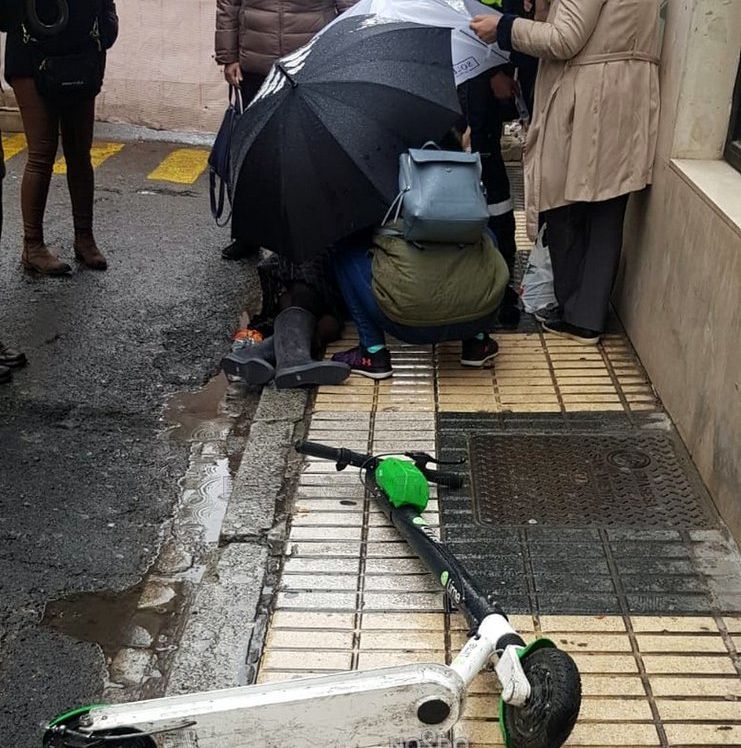 Varias personas asisten a la mujer herida, junto al patinete que provocó el suceso.