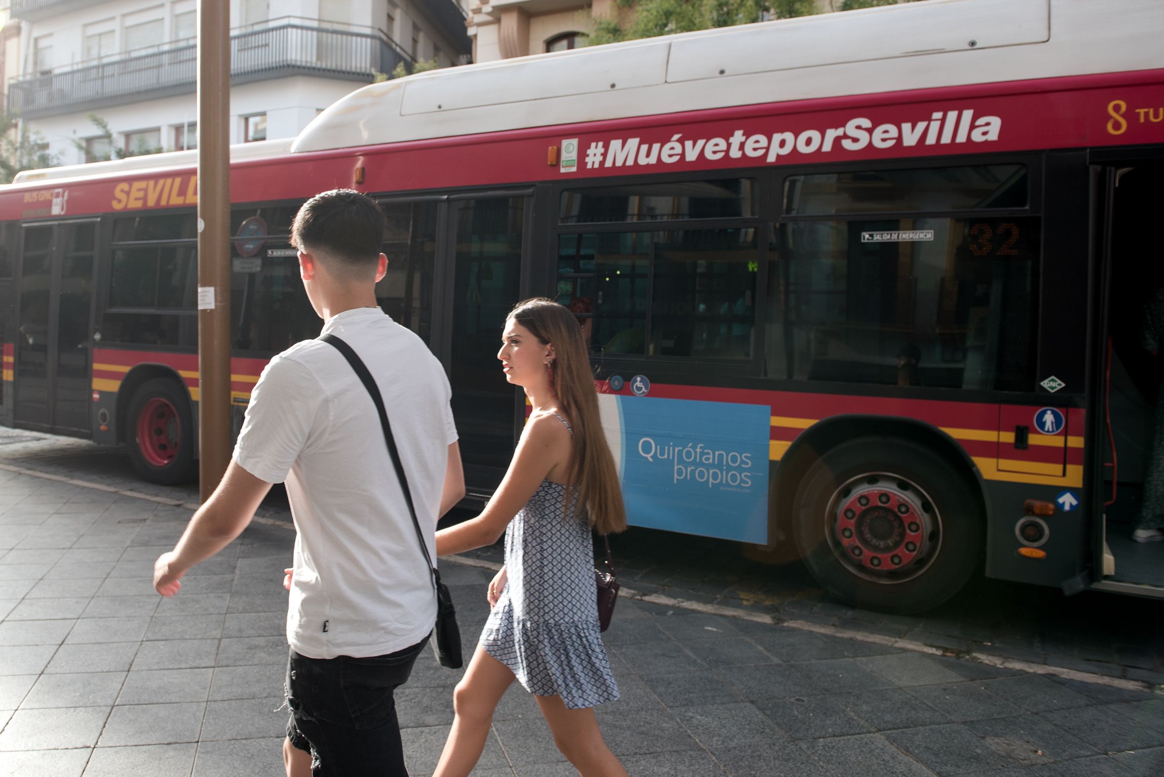 Dos personas pasan junto a un autobús de Tussam.