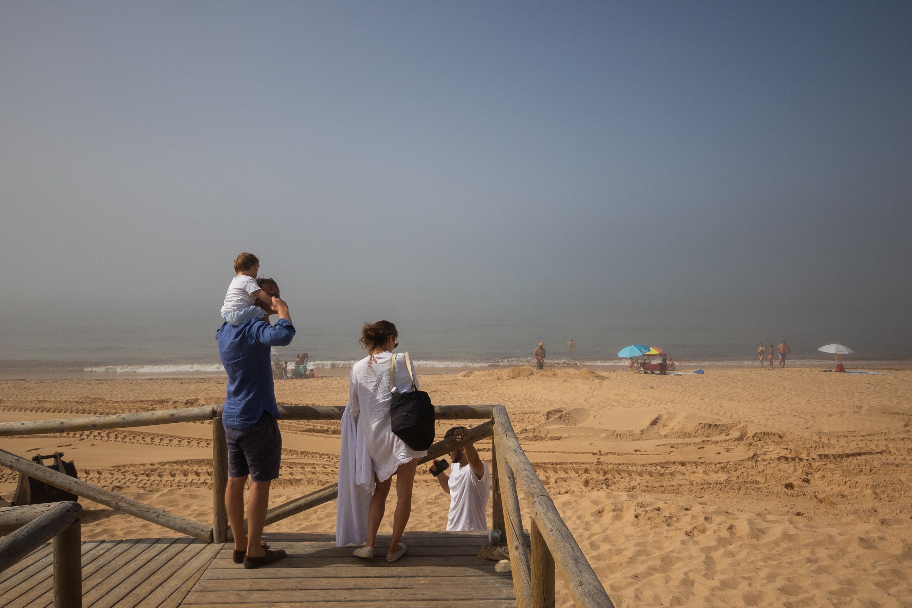 Una familia extranjera observa el estado de la playa de Marisucia. 
