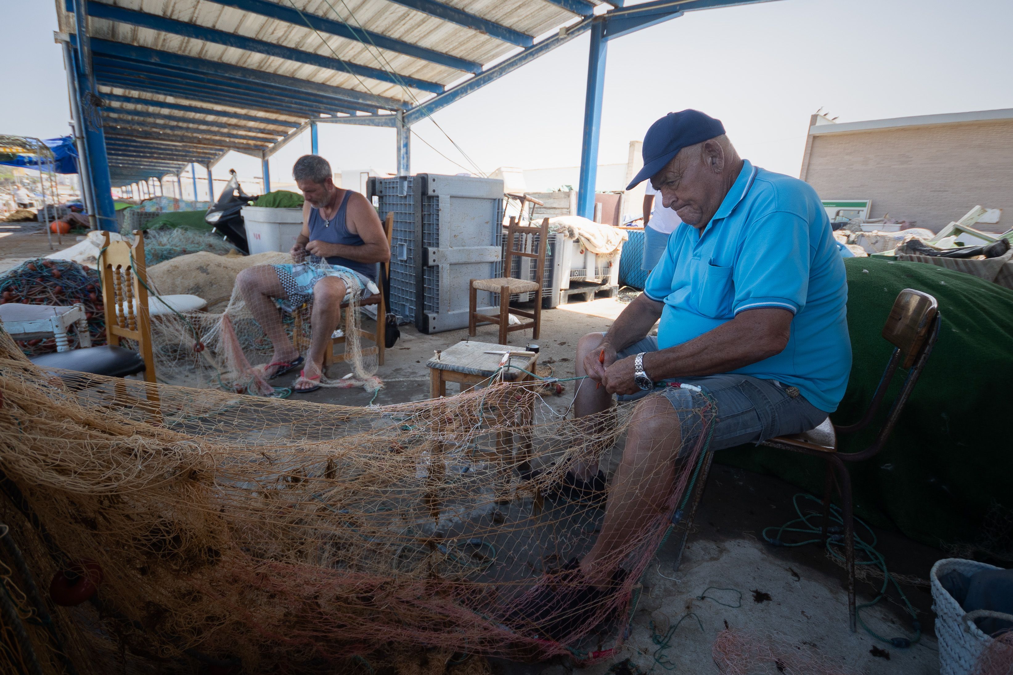 Los pescadores intentan reparar las artes dañadas por el alga invasora. 