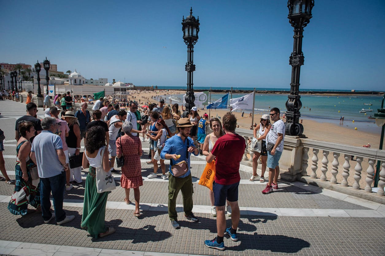 Un grupo de turistas acompaña a un guía en la playa de La Caleta este lunes 24 de julio.    MAURI BUHIGAS