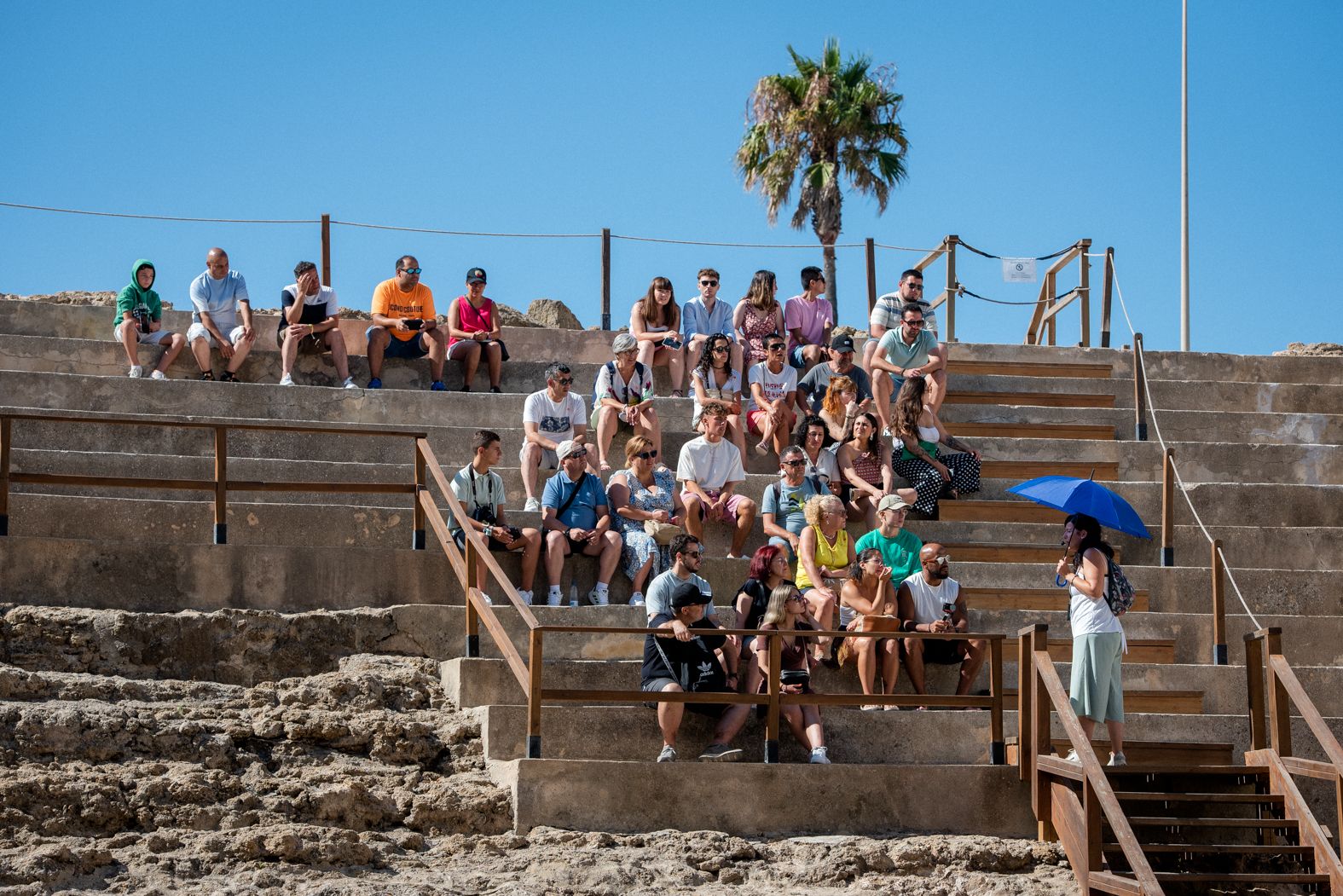 Un grupo de turistas atiende a la guía en el Teatro Romano de Cádiz, en verano de 2023.