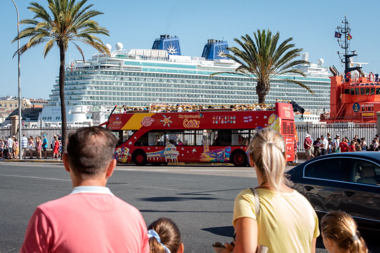 Cruceristas forman cola ante un autobús turístico frente a una de las grandes embarcaciones.