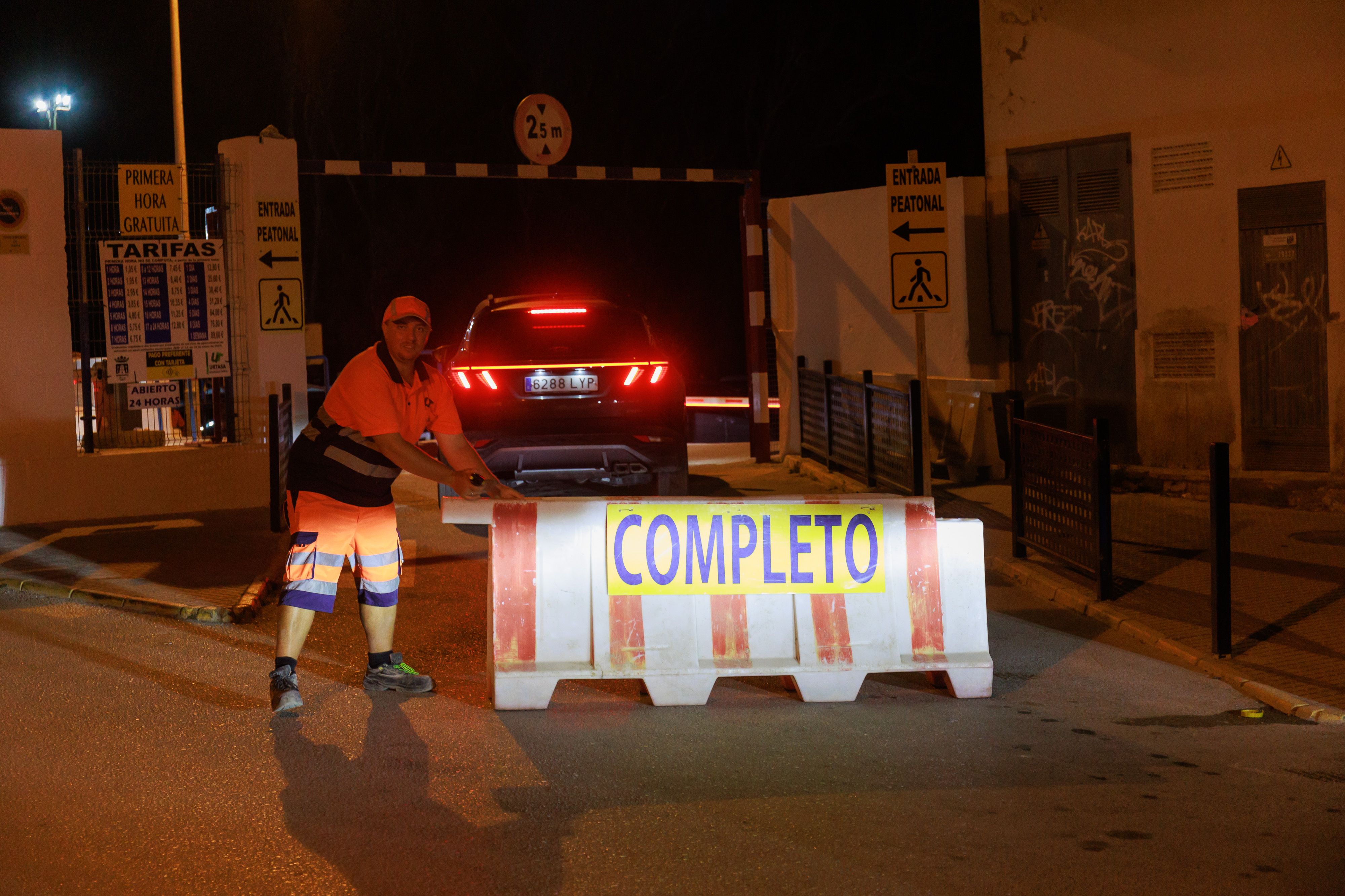 Un trabajador pone la valla con el cartel de completo en el parking municipal de Tarifa. 