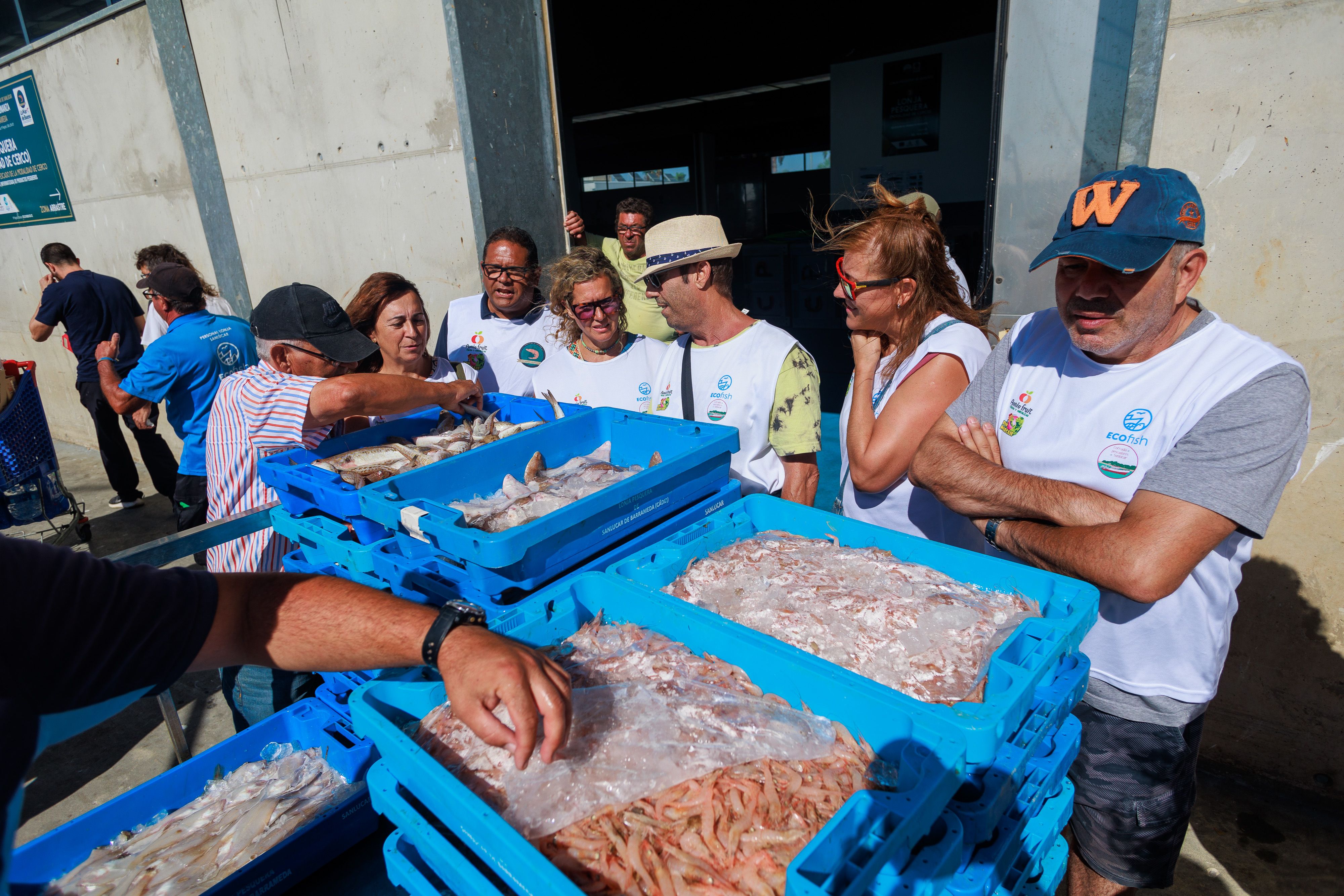 Los turistas, junto a las cajas al descargar en el muelle.