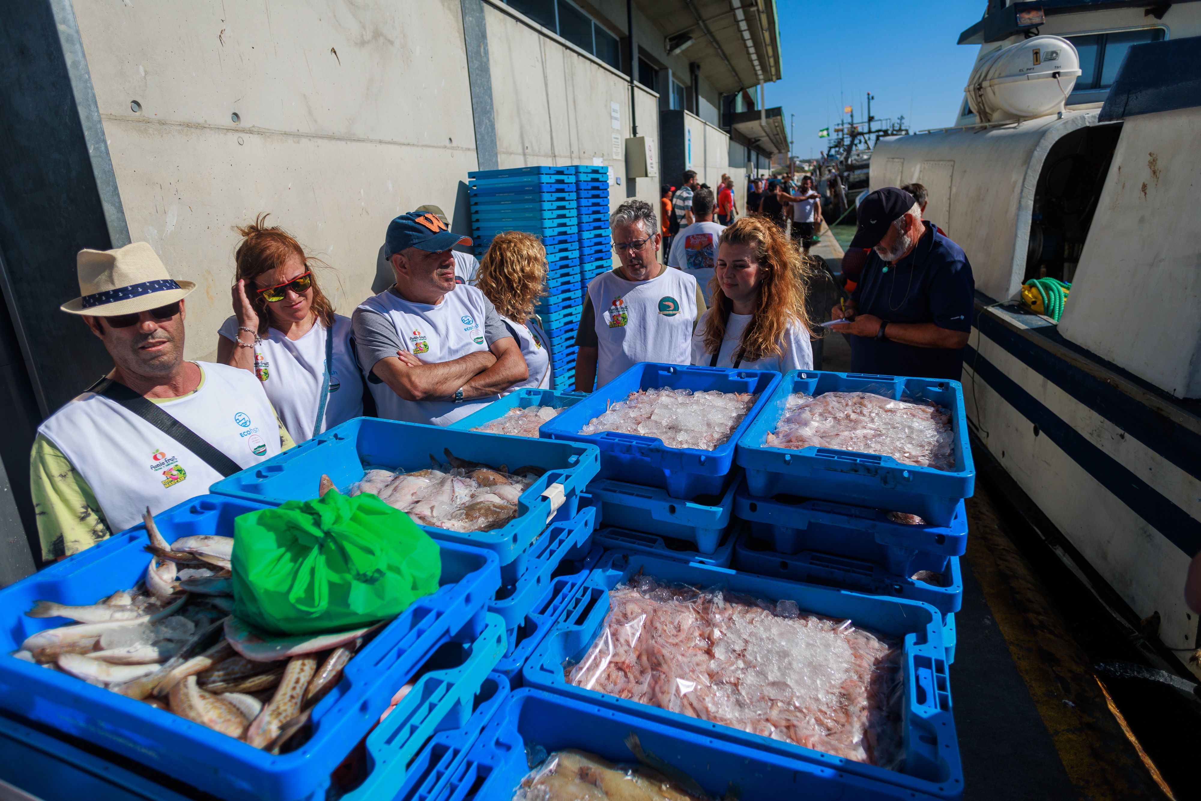 Los turistas, junto a las cajas al descargar en el muelle.