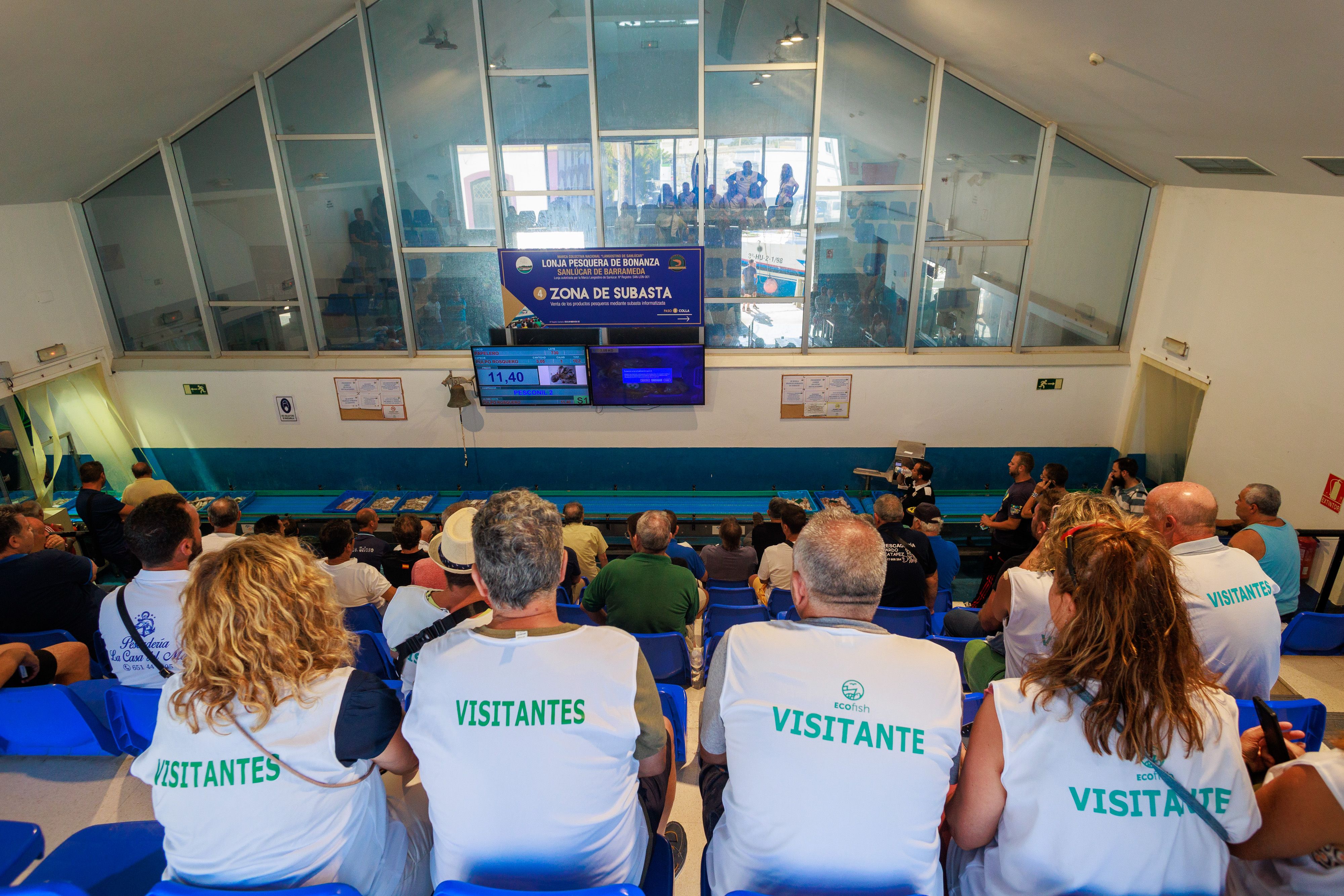Los visitantes, junto a los compradores en la galería de la subasta.