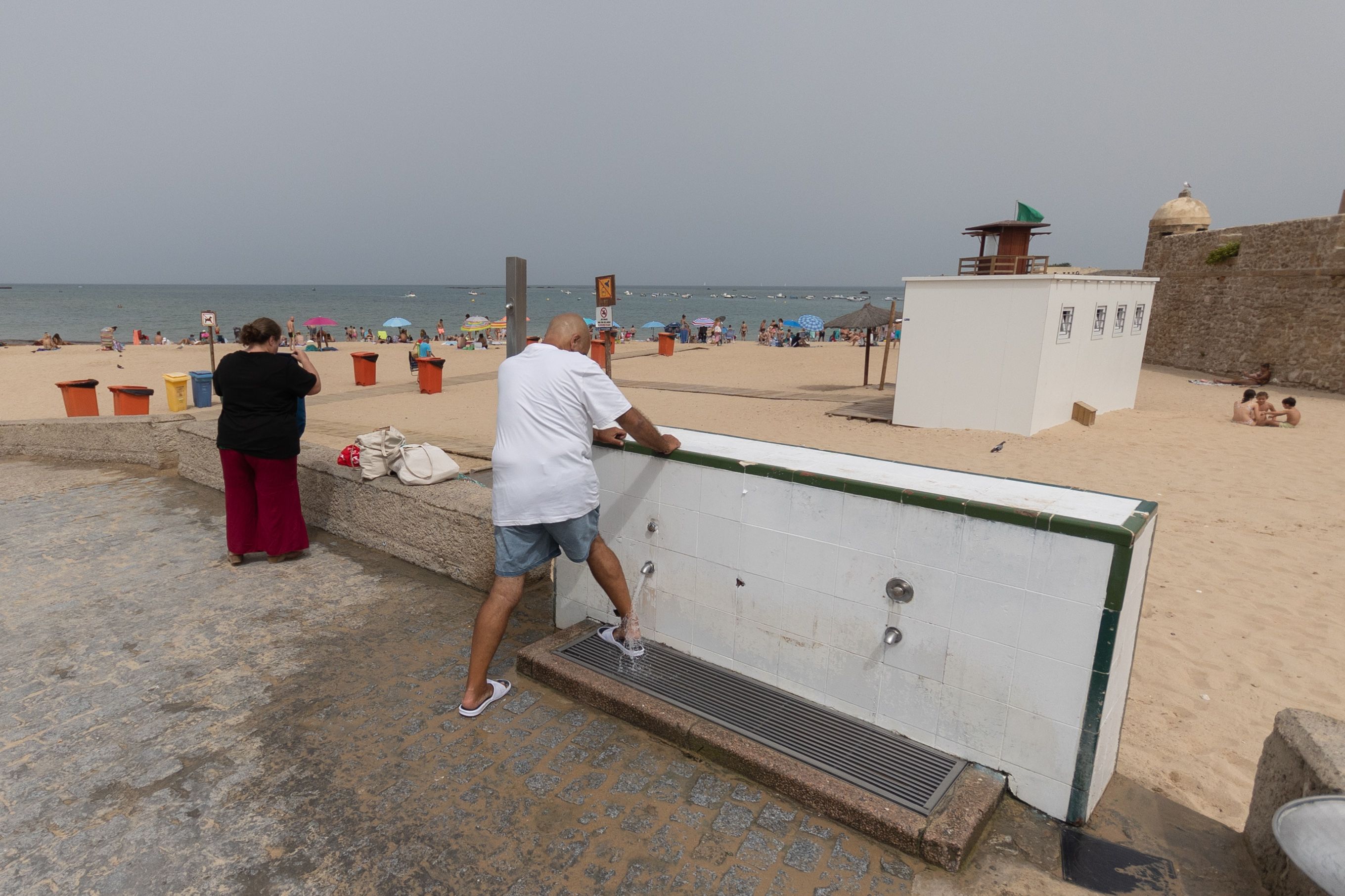 Un hombre se lava los pies al salir de la playa en Cádiz este miércoles.