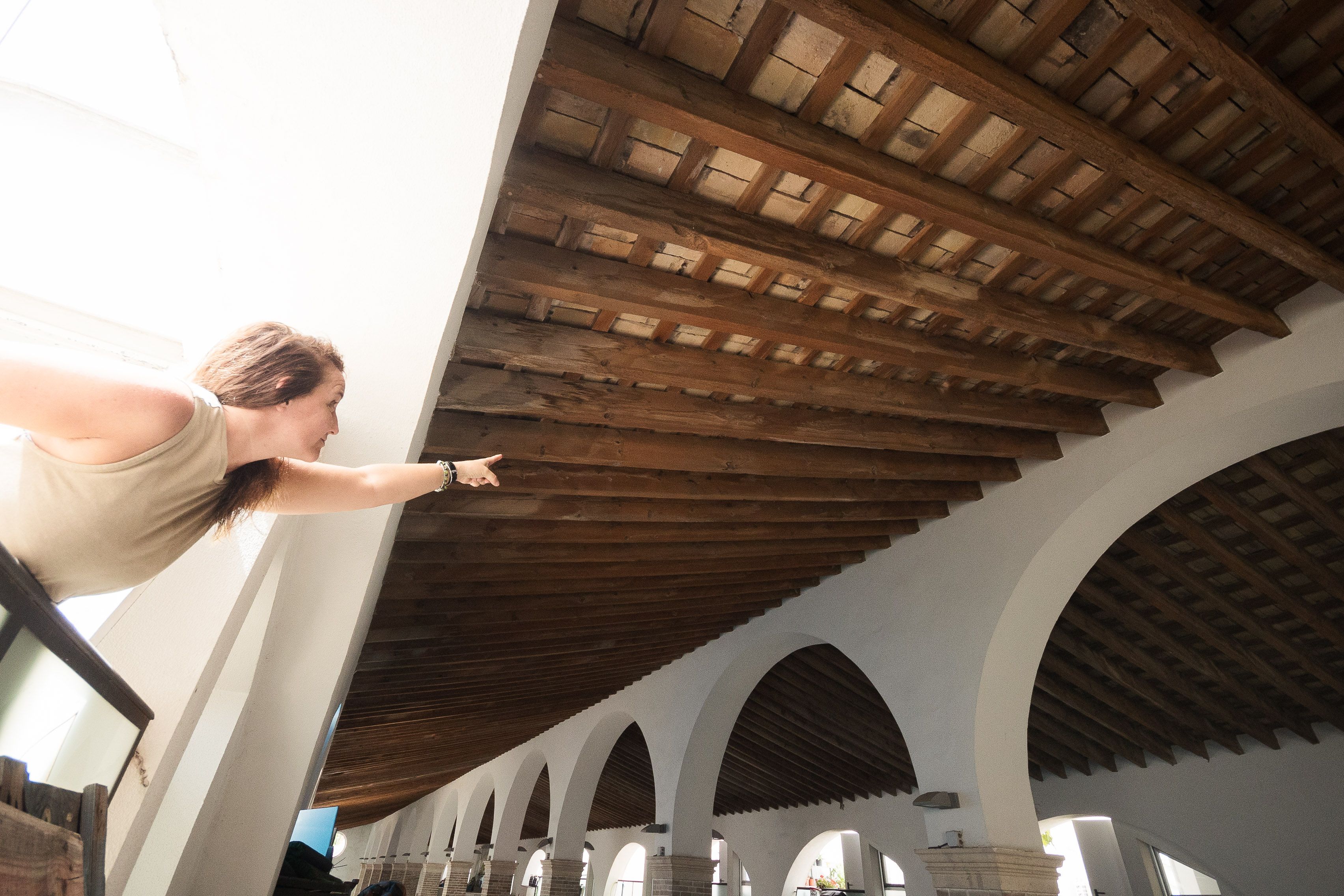 La presidenta señalando estado de las vigas interiores en las viviendas de la bodega rehabilitada.
