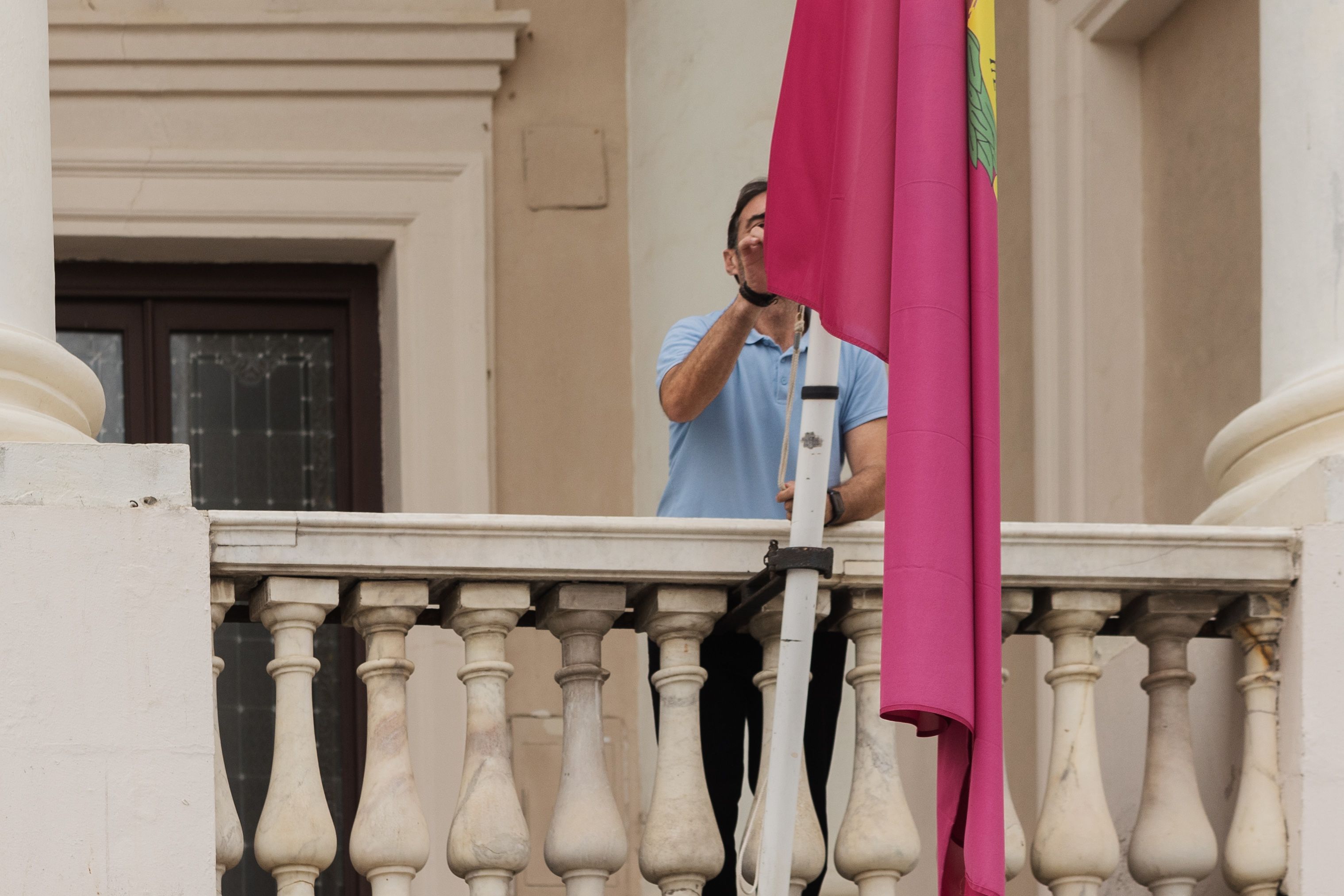 Un conserje arría una bandera en el Ayuntamiento de Cádiz: día de luto.