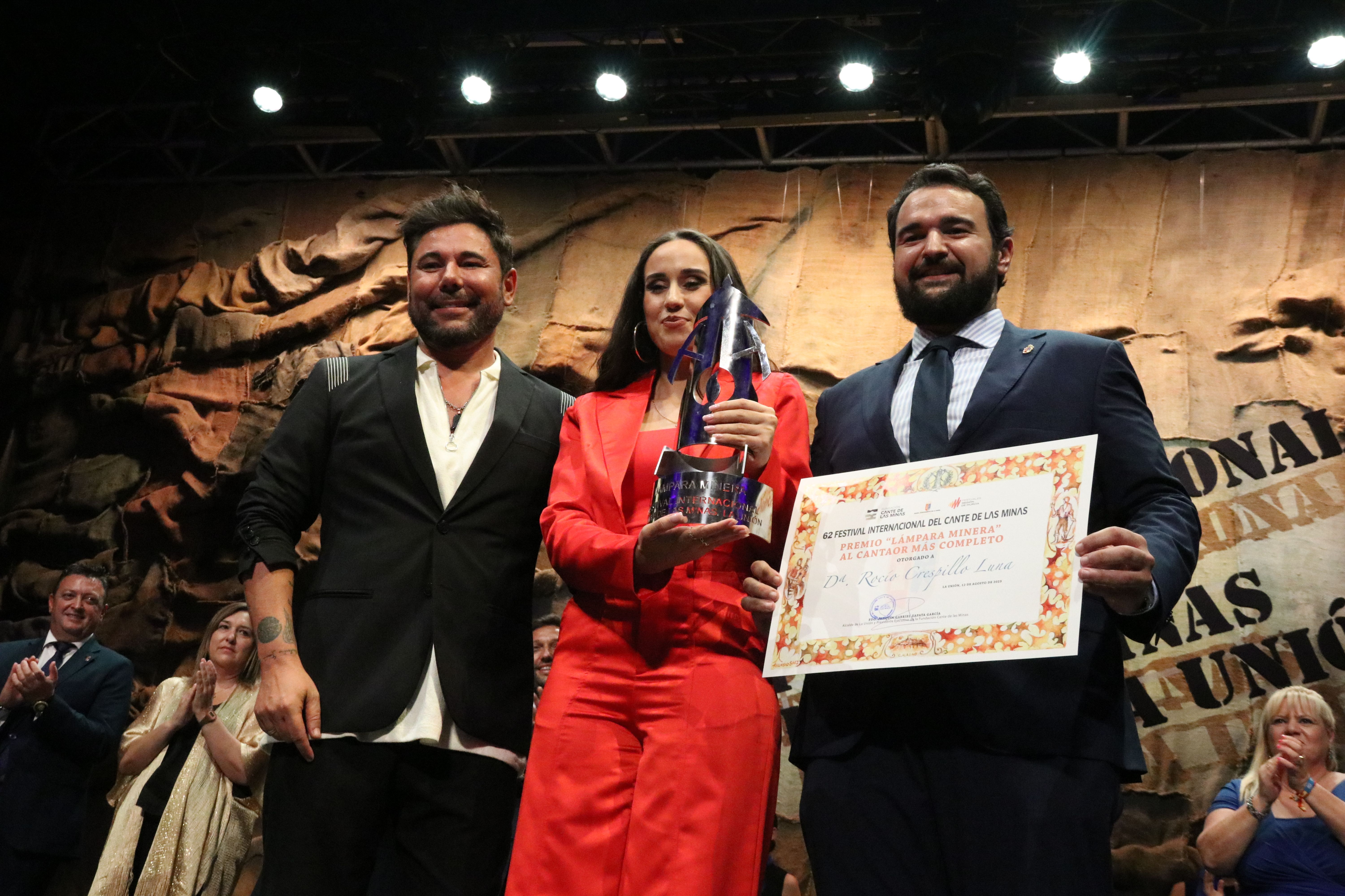 Rocio Luna recibiendo de manos de Miguel Poveda y el alcalde de La Unión la Lámpara Minera del Festival Internacional de Cante de Las Minas 2023