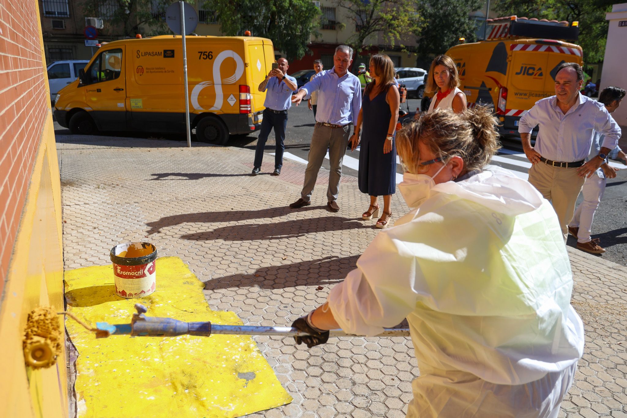Plan de choque en Sevilla para mejorar los entornos de los colegios antes del inicio del curso. En la imagen, una operadora pintado un colegio, con la supervisión del alcalde. 