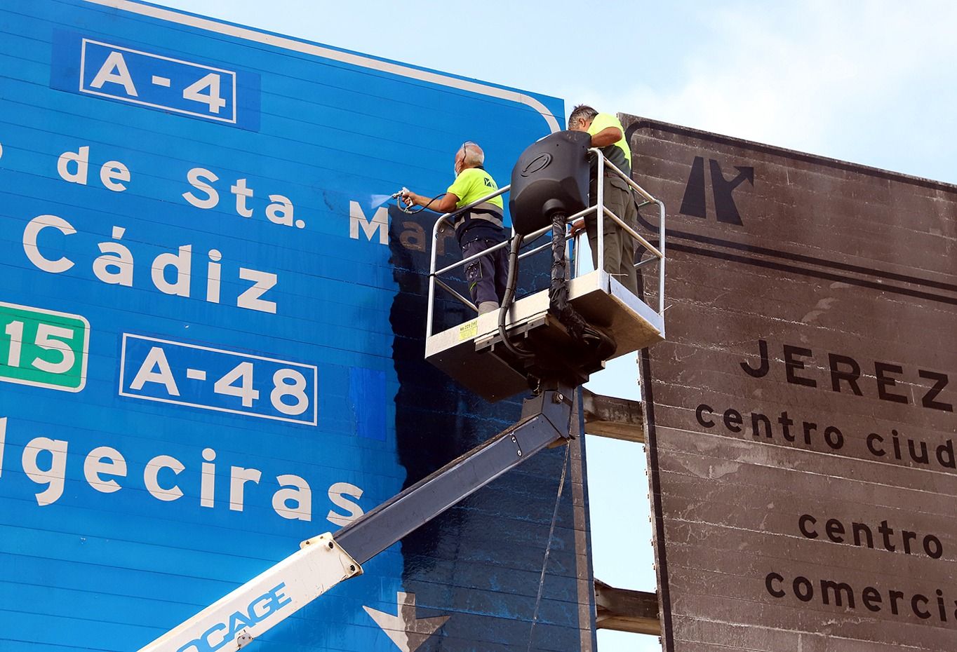 Así lucen los paneles de señalización y de las entradas a Jerez por la zona sur. En la imagen, operarios trabajando en las señales.