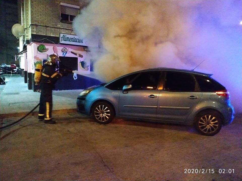 Bomberos sofocan las llamas de un vehículo en llamas, fruto de la reyerta en el 'Mopu'.