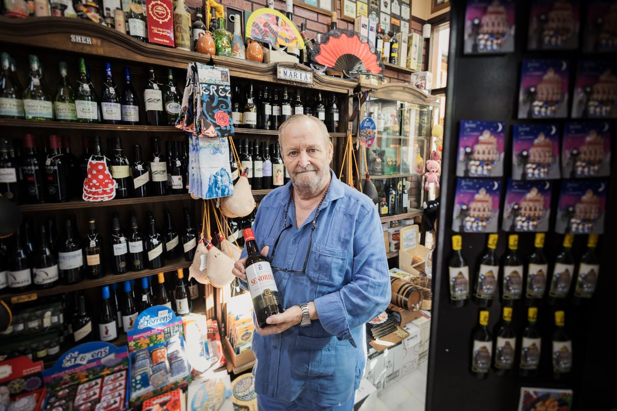 Manuel Díaz, junto a muchas de las botellas de vino que vende en su tienda. 