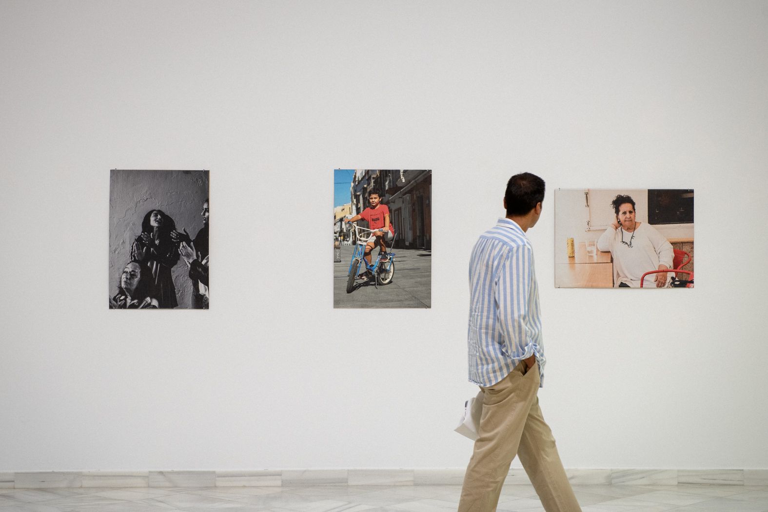 Un hombre observa las fotografías de la muestra.
