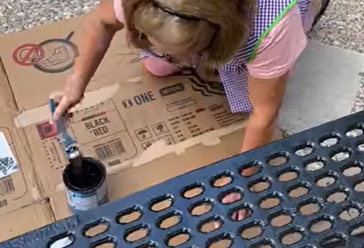 Una vecina pinta un banco del barrio La Aspirina en Trebujena.  